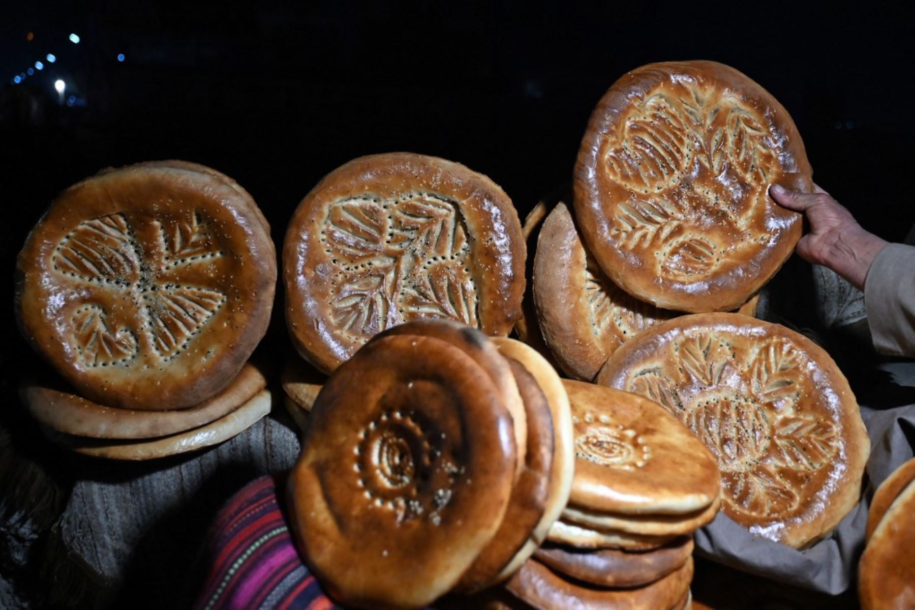 Esta fotografía muestra a un vendedor afgano vendiendo panes planos tradicionales conocidos localmente como Naan, en un mercado de carretera en Kabul. Para muchos en Afganistán, uno de los países más pobres del mundo, donde 12,4 millones de personas viven en inseguridad alimentaria aguda, según el Programa Mundial de Alimentos, el pan constituye la mayor parte de las comidas. El pan afgano es uno de los pocos alimentos que todo el mundo puede permitirse, con precios tan bajos como 10 afganos (0,14) centavos. Foto: AFP