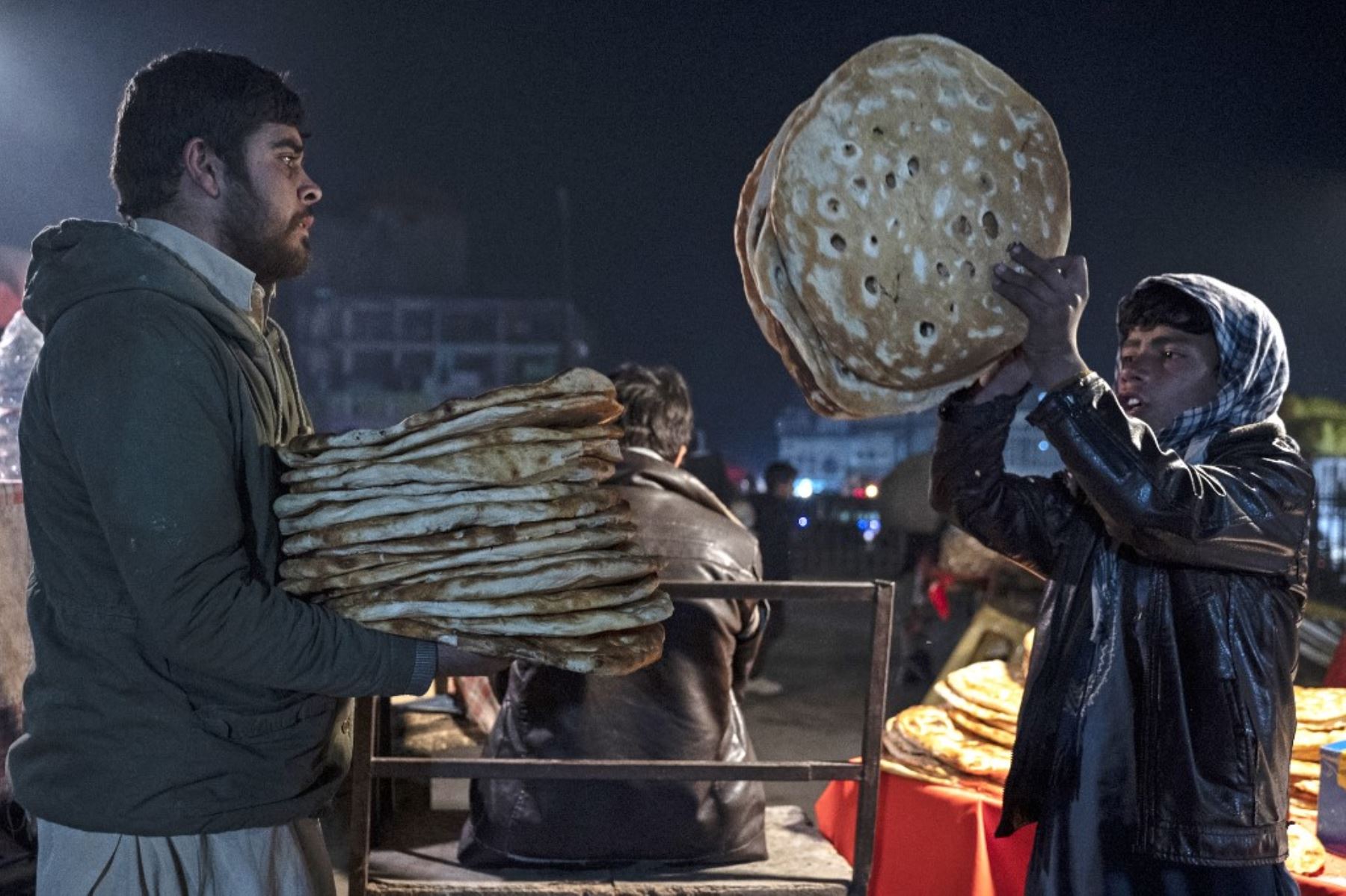 Esta fotografía muestra a vendedores afganos vendiendo panes planos tradicionales conocidos localmente como Naan, en un mercado de carretera en Kabul. Para muchos en Afganistán, uno de los países más pobres del mundo, donde 12,4 millones de personas viven en inseguridad alimentaria aguda, según el Programa Mundial de Alimentos, el pan constituye la mayor parte de las comidas. El pan afgano es uno de los pocos alimentos que todo el mundo puede permitirse, con precios tan bajos como 10 afganos (0,14) centavos. Foto: AFP