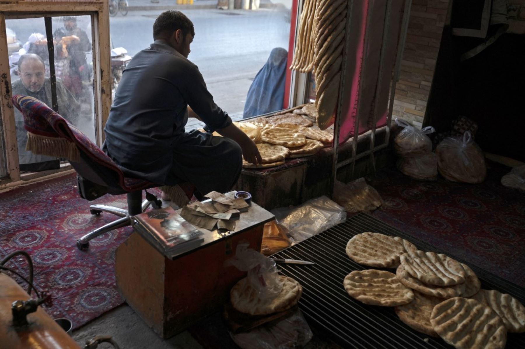 Esta fotografía muestra a un panadero afgano arreglando panes planos tradicionales conocidos localmente como Naan, mientras espera a los clientes en una panadería de Kabul. Para muchos en Afganistán, uno de los países más pobres del mundo, donde 12,4 millones de personas viven en inseguridad alimentaria aguda, según el Programa Mundial de Alimentos, el pan constituye la mayor parte de las comidas. El pan afgano es uno de los pocos alimentos que todo el mundo puede permitirse, con precios tan bajos como 10 afganos (0,14) centavos. Foto: AFP