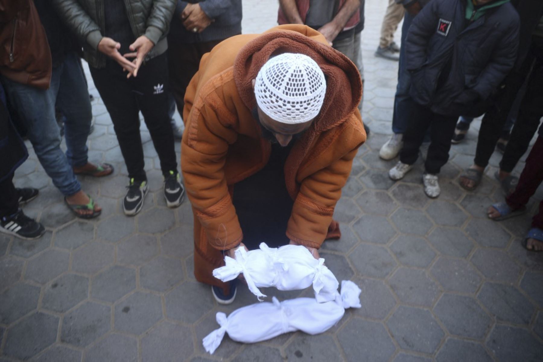 Un hombre palestino coloca el cuerpo envuelto del recién nacido Jumaa al-Batran, que supuestamente murió debido a hipotermia, junto al cadáver envuelto de otro niño antes de su funeral ante una oración por los muertos en el hospital Aqsa Martyrs en Deir el-Balah el 29 de diciembre de 2024, en medio de la guerra en curso entre Israel y el movimiento palestino Hamas. Los funcionarios de salud de Gaza dijeron que un bebé de 20 días murió el 29 de diciembre de "resfriado severo" mientras el territorio palestino