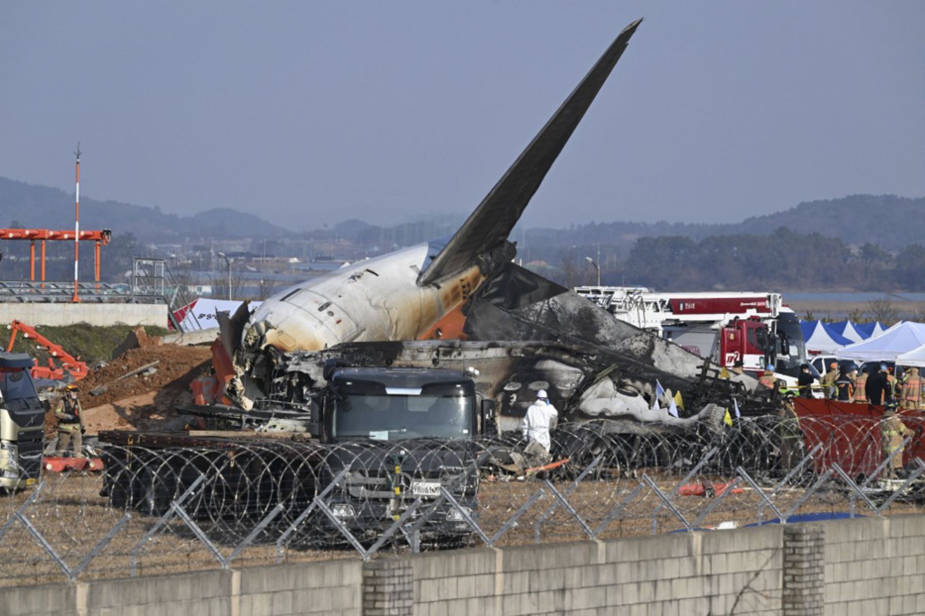 Los bomberos y el personal de rescate trabajan cerca de los restos de un avión de la serie Boeing 737-800 de Jeju Air después de que el avión se estrellara y estallara en llamas en el Aeropuerto Internacional de Muan en la provincia de South Jeolla, a unos 288 kilómetros al suroeste de Seúl el 29 de diciembre de 2024. Un avión de Jeju Air que transportaba a 181 personas de Bangkok a Corea del Sur se estrelló al llegar el 29 de diciembre, chocando con una barrera y estallando en llamas, con solo dos superviv