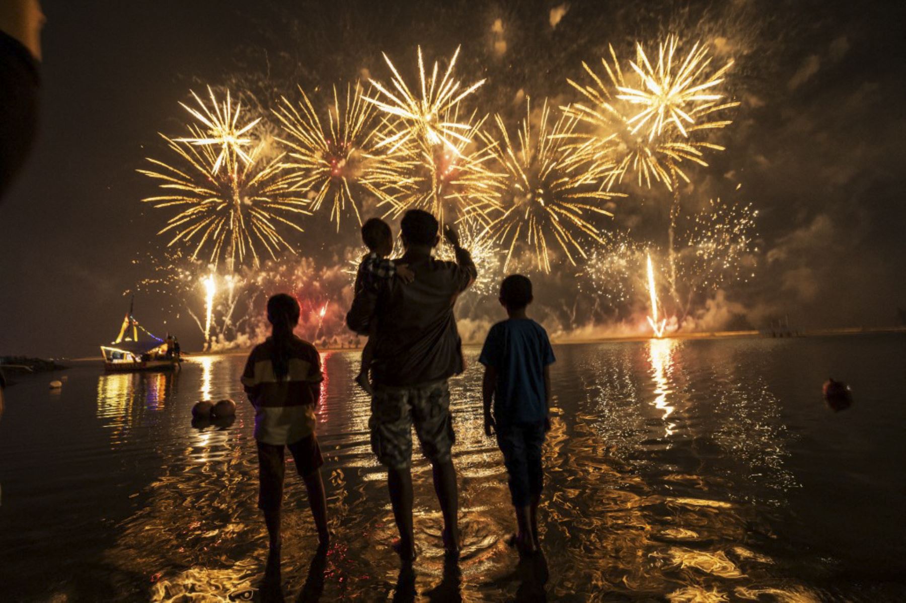 Miembros de una familia aprecian los fuegos artificiales mientras celebran el Año Nuevo en Ancol Beach en Yakarta el 1 de enero de 2025. (Foto de Yasuyoshi CHIBA / AFP)