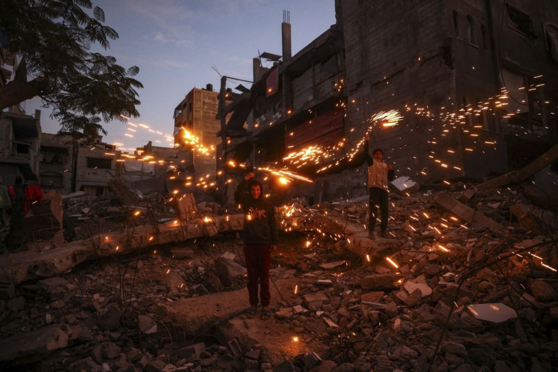 Niños juegan con fuegos artificiales en el campamento de Bureij para palestinos desplazados el 30 de diciembre de 2024, en medio de la continua guerra entre Israel y el grupo militante Hamas. Desde que la guerra entre Israel y Hamas comenzó en octubre del año pasado, los 2,4 millones de residentes de Gaza han sufrido una grave escasez de electricidad, agua potable, alimentos y servicios médicos. (Foto de Eyad BABA / AFP)