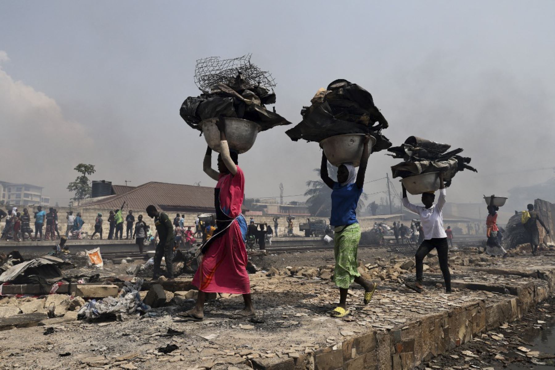 La gente intenta rescatar artículos del mercado de ropa de segunda mano quemado en Kantamanto en Accra, Ghana, el 2 de enero de 2025. El incendio en el mercado de Kantamanto comenzó en las primeras horas de la mañana, destruyendo una gran parte de la zona y desplazando a miles de comerciantes. (Foto de Nipah Dennis / AFP)