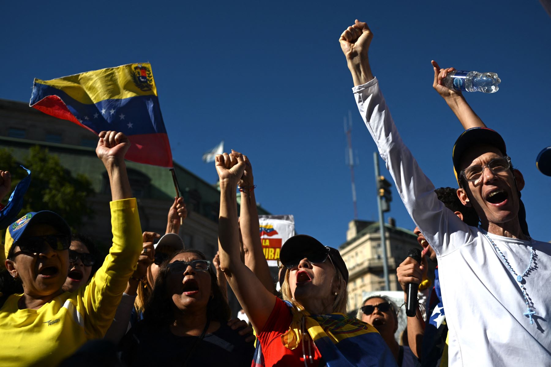 Los residentes venezolanos gritan consignas mientras levantan los brazos durante una protesta en vísperas de la toma de posesión del presidente de Venezuela, Nicolás Maduro, en Buenos Aires. AFP