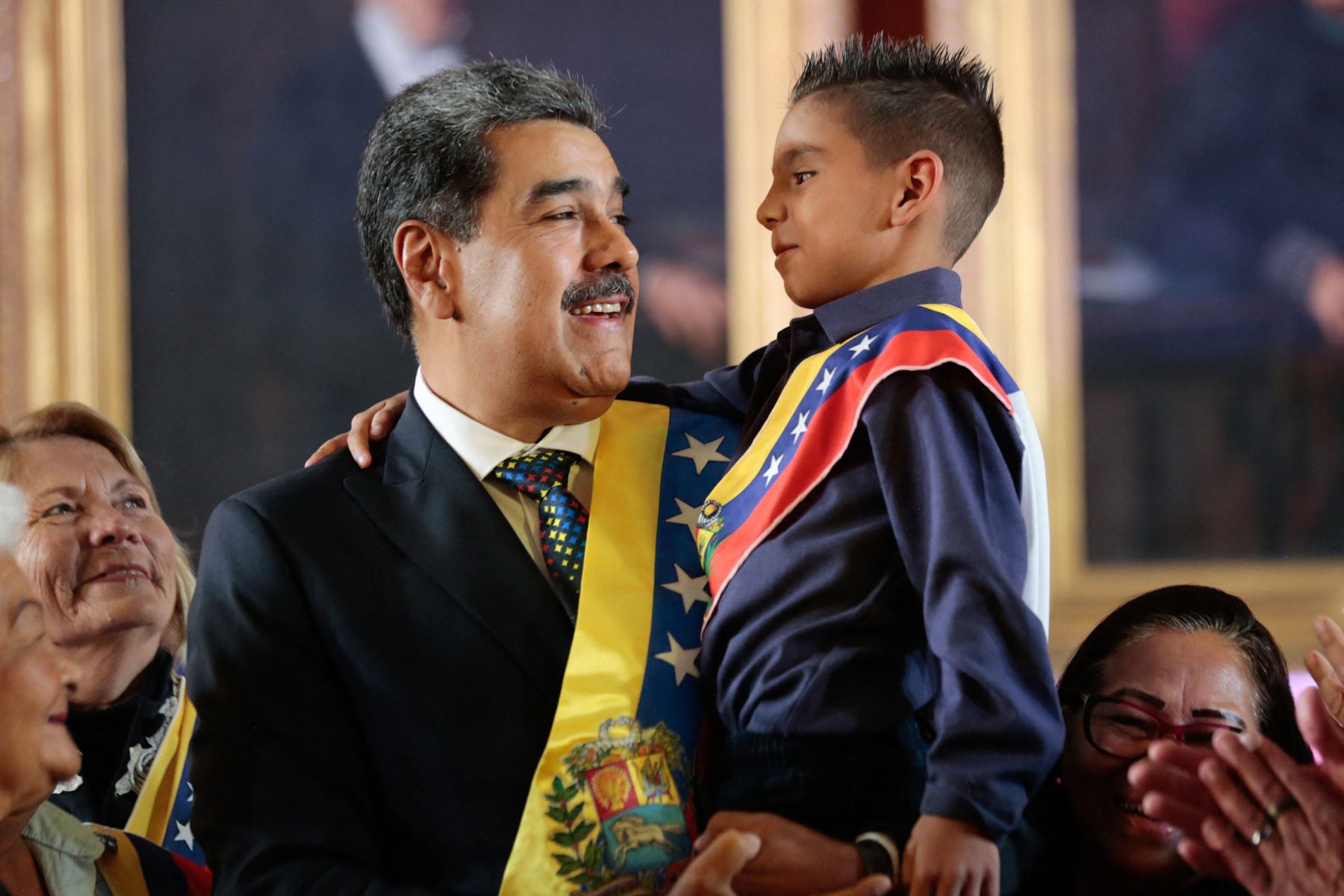 Nicolás Maduro, sosteniendo a un niño después de prestar juramento durante la toma de posesión presidencial en el Capitolio -sede de la Asamblea Nacional- en Caraca. AFP