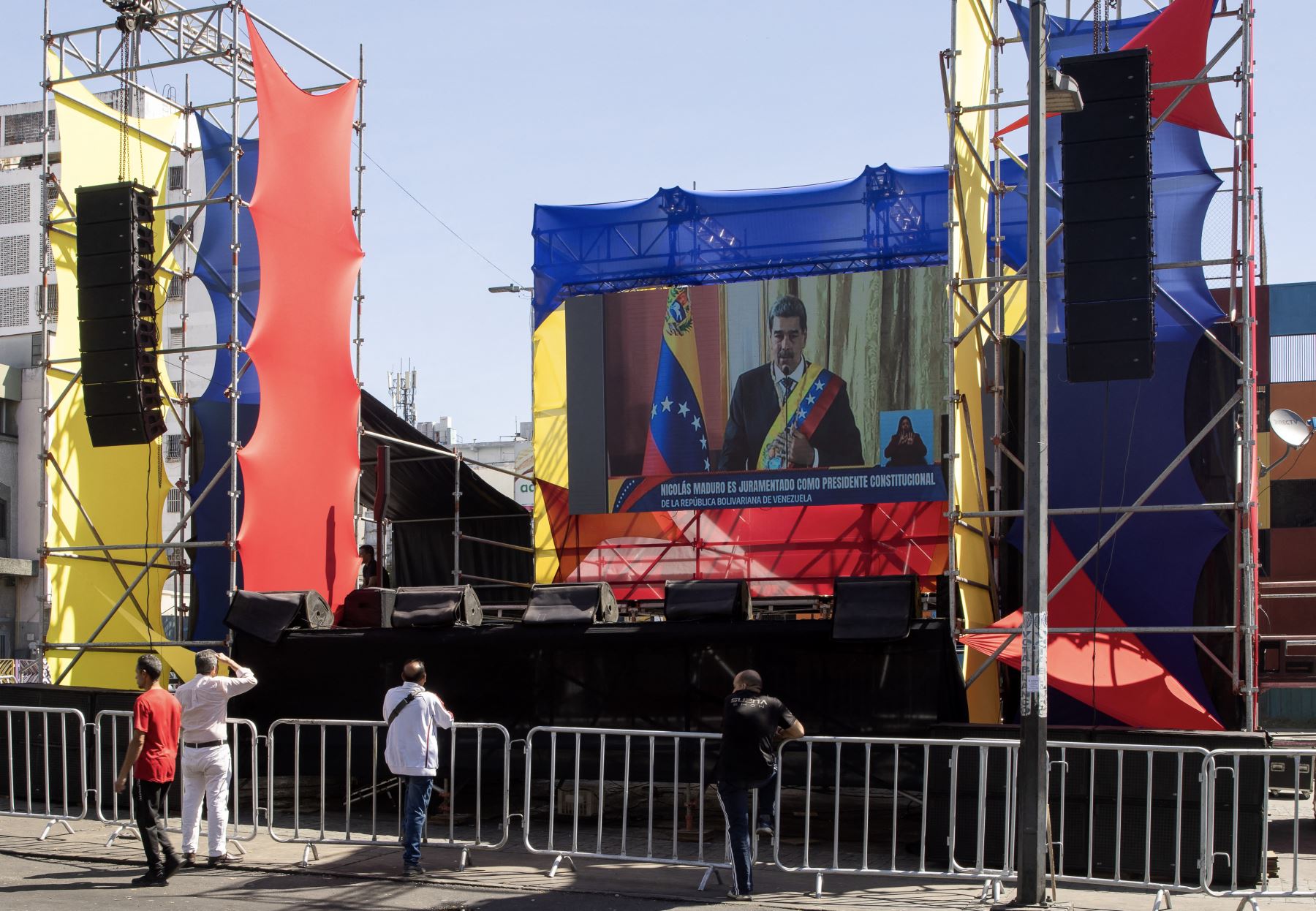 Los transeúntes observan la toma de posesión presidencial del presidente de Venezuela, Nicolás Maduro, en una pantalla gigante en la calle, en Caracas. AFP