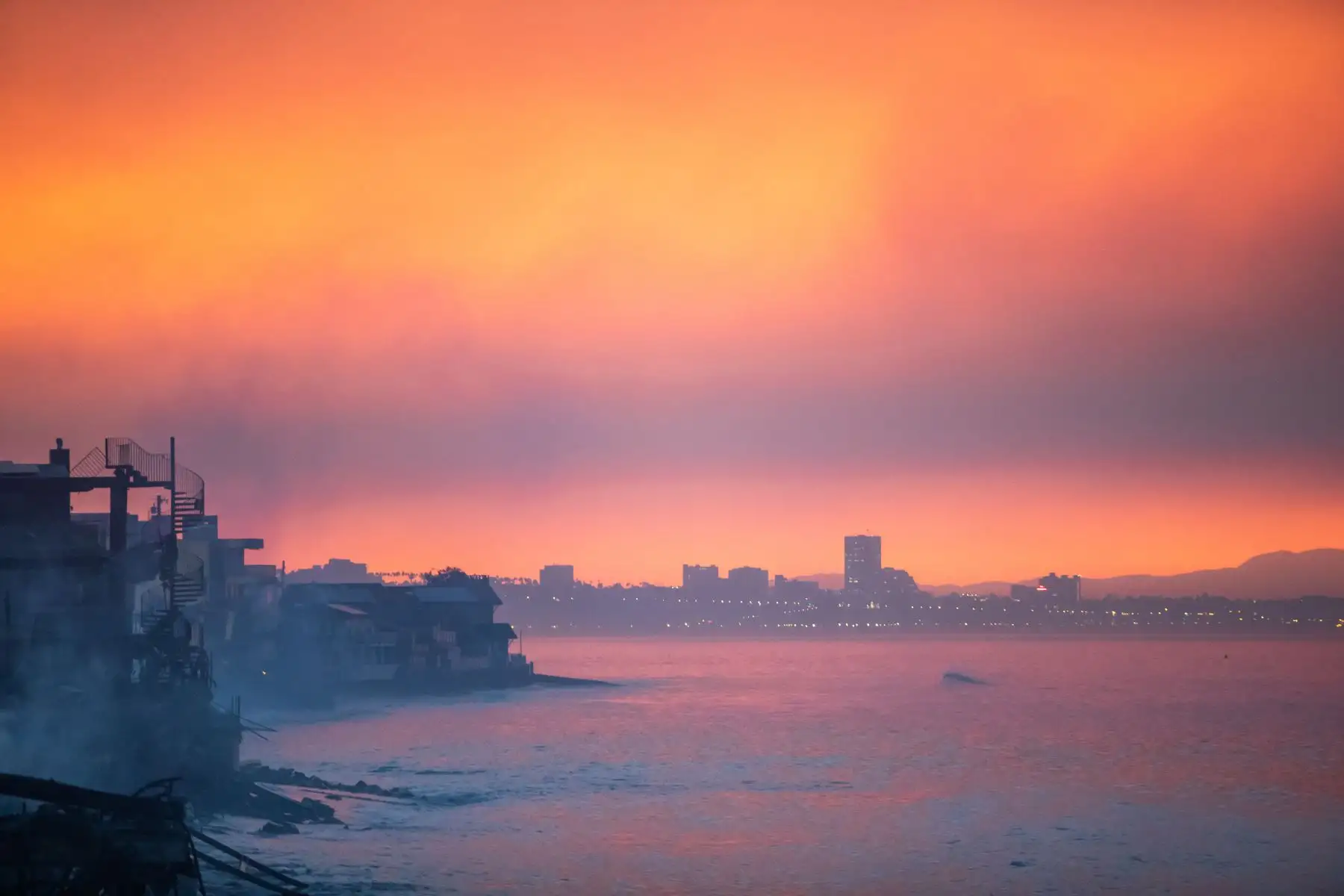 El humo de los incendios forestales y las casas quemadas por el incendio Palisades se ven en la madrugada del 10 de enero de 2025 en el barrio de Pacific Palisades de Los Ángeles, California. AFP