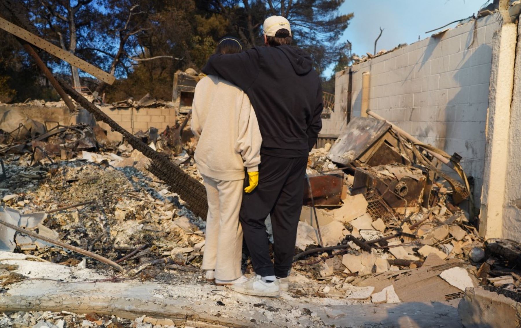 Kyle Kucharski abraza a su compañera Nicole Perri mientras están de pie en las ruinas de su casa destruida por el incendio de Palisades en el vecindario de Pacific Palisades de Los Ángeles, California, el 10 de enero de 2025. Foto: AFP