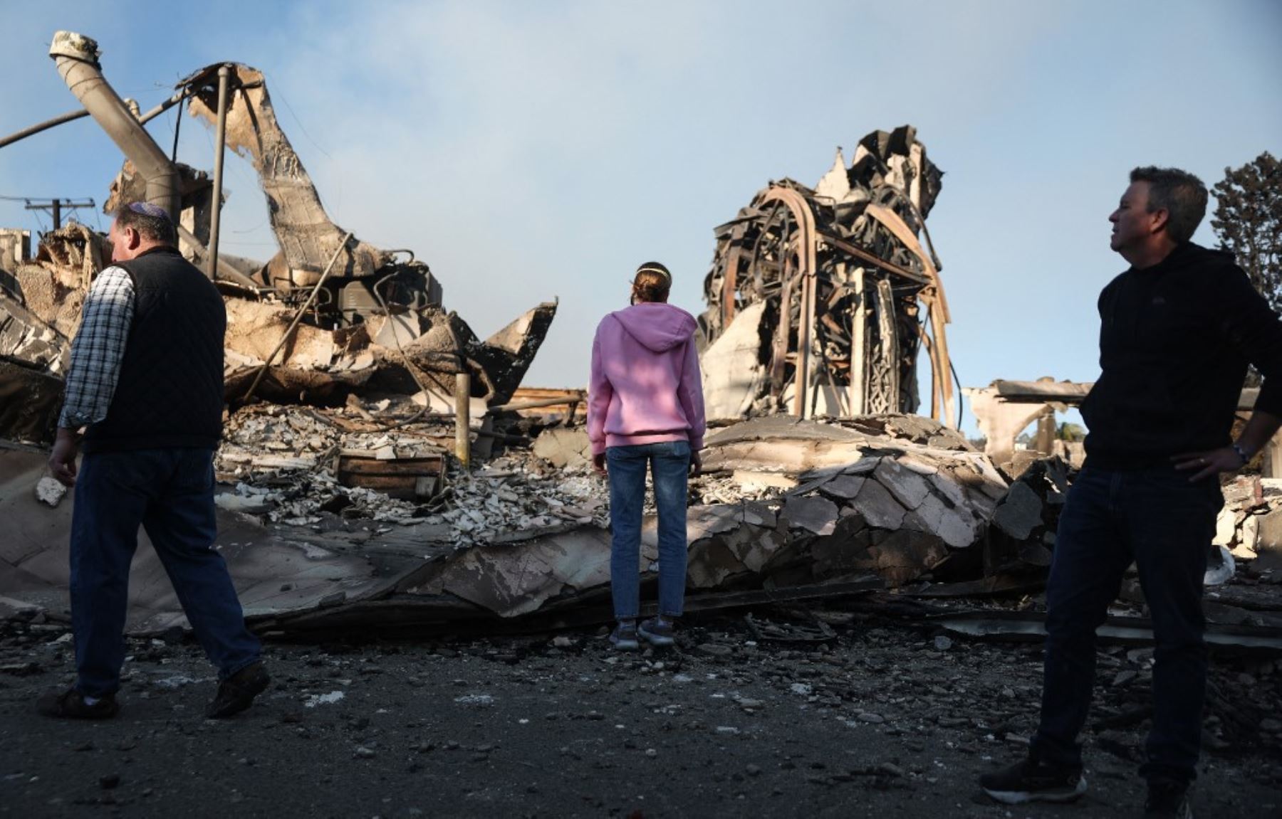 El reverendo John Shaver (R) observa mientras visita los restos de la Iglesia Metodista Unida de la Comunidad, donde es pastor, mientras los incendios forestales causan daños y pérdidas en el condado de Los Ángeles. Foto: AFP