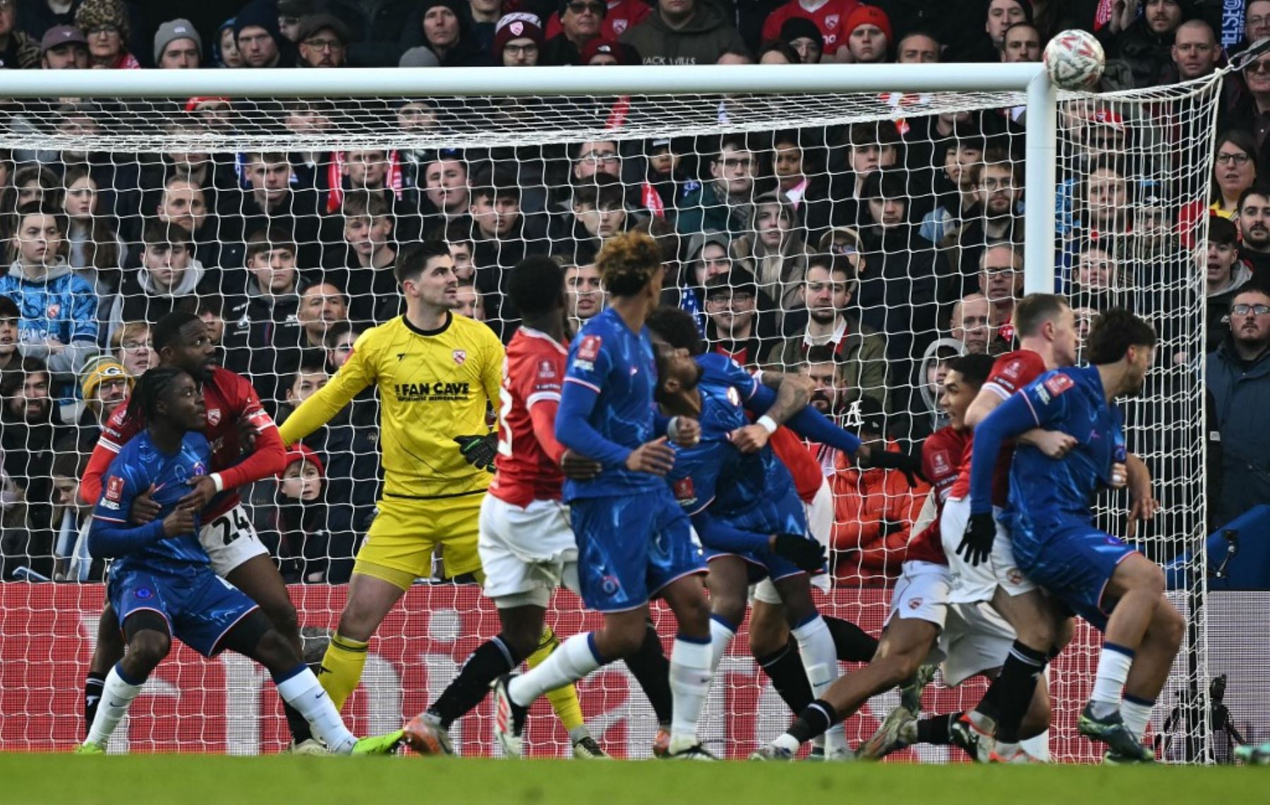 El portero inglés #01 de Morecambe, Harry Burgoyne, observa cómo el balón golpea la barra después de que el defensor inglés del Chelsea #04 Tosin Adarabioyo (C) se dirigiera hacia la portería durante el partido de fútbol de tercera ronda de la Copa FA inglesa entre Chelsea y Morecambe en Stamford Bridge en Londres el 11 de enero de 2025. (Foto de Ben STANSALL / AFP)