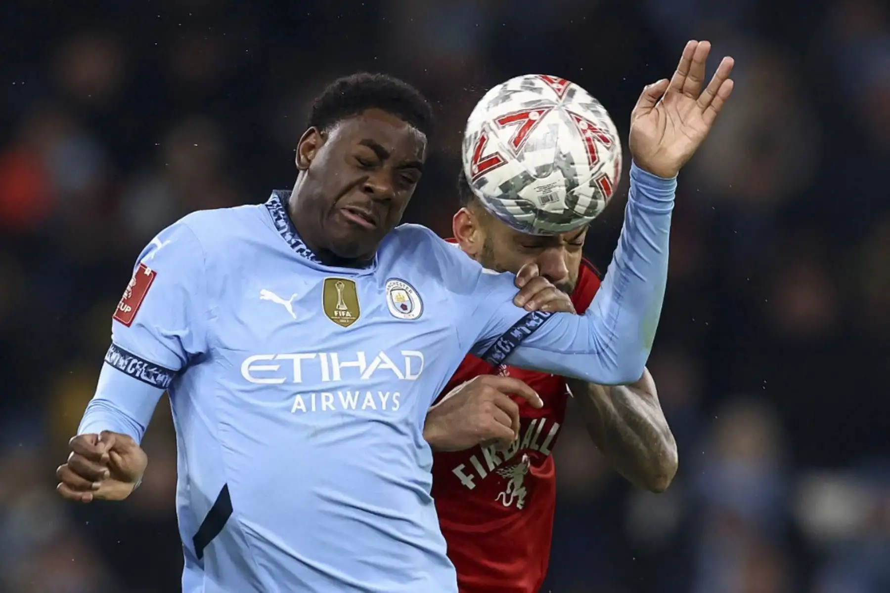 El delantero inglés del Manchester City #67 Divin Mubama (Iq) y el defensor jamaicano del Salford City #16 Curtis Tilt (R) compiten por cabecear el balón durante el partido de fútbol de tercera ronda de la Copa FA inglesa entre el Manchester City y el Salford City en el Etihad Stadium de Manchester, noroeste de Inglaterra, el 11 de enero de 2025. (Foto de Darren Staples / AFP)