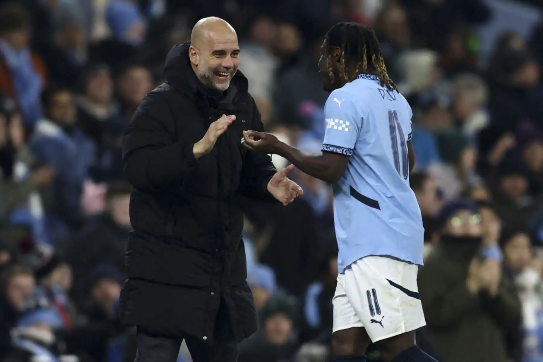 El entrenador español del Manchester City, Pep Guardiola (L), felicita al centrocampista belga #11 del Manchester City, Jeremy Doku, cuando abandona el campo después de ser sustituido durante el partido de fútbol de la tercera ronda de la FA Cup inglesa entre el Manchester City y el Salford City en el Etihad Stadium de Manchester, al noroeste de Inglaterra, el 11 de enero de 2025. (Foto de Darren Staples / AFP)