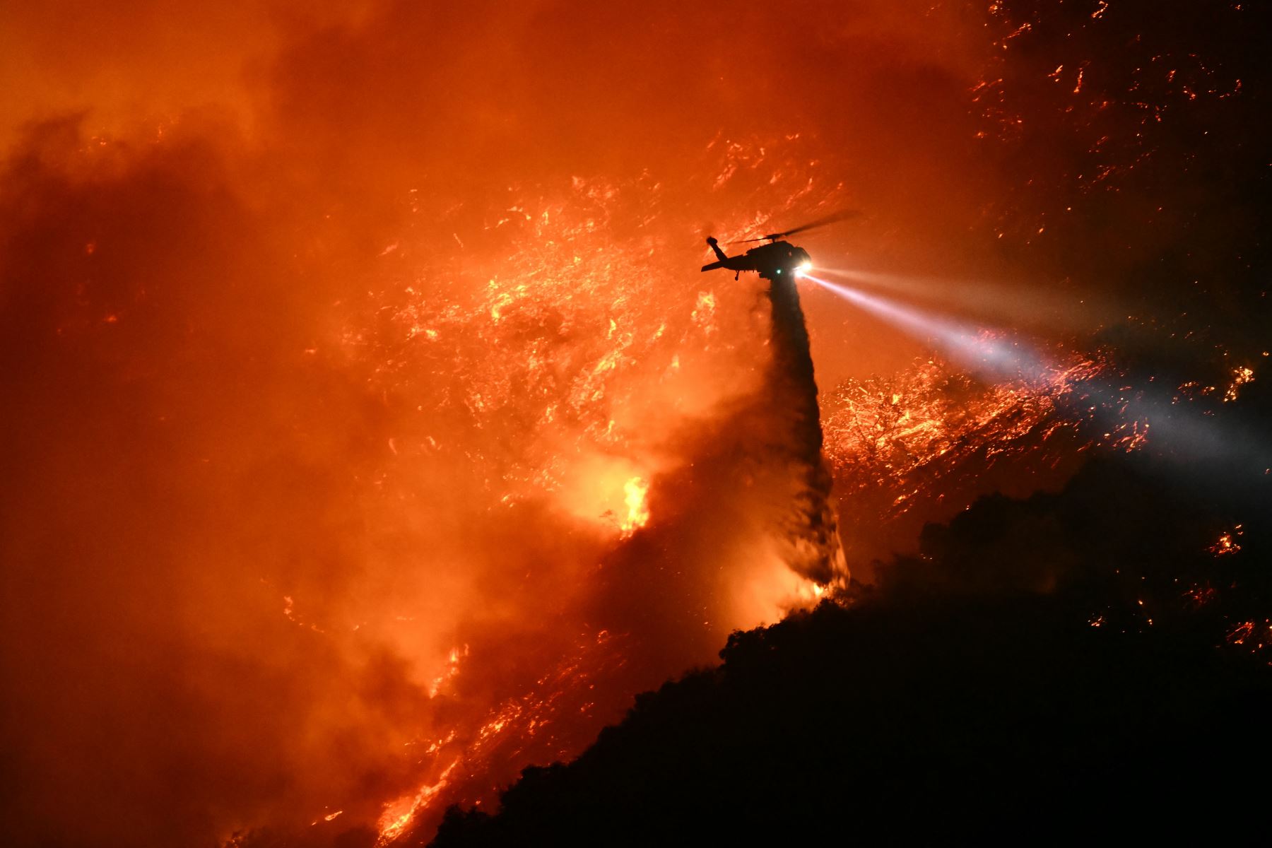 Un helicóptero de extinción de incendios arroja agua mientras el incendio de Palisades crece cerca del vecindario de Mandeville Canyon y Encino, California.
Foto: AFP