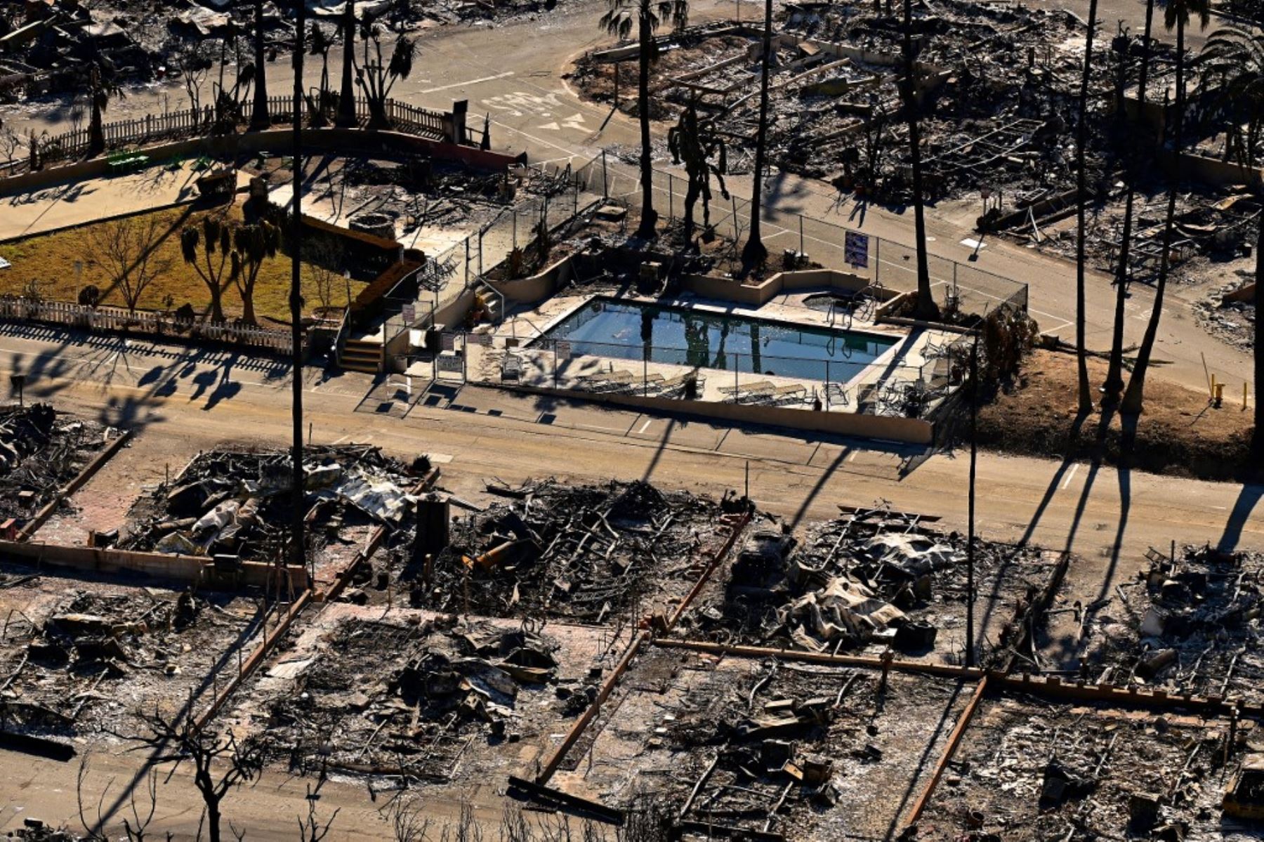 Una piscina se encuentra junto a casas carbonizadas y automóviles quemados entre los escombros del Pacific Palisades Bowl Mobile Estates devastado por los incendios en Los Ángeles, California, el 13 de enero de 2025. Foto: AFP