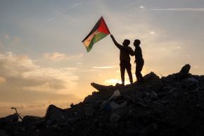 Un niño ondea una bandera palestina sobre escombros en un campamento para desplazados en la Franja de Gaza, Foto: AFP