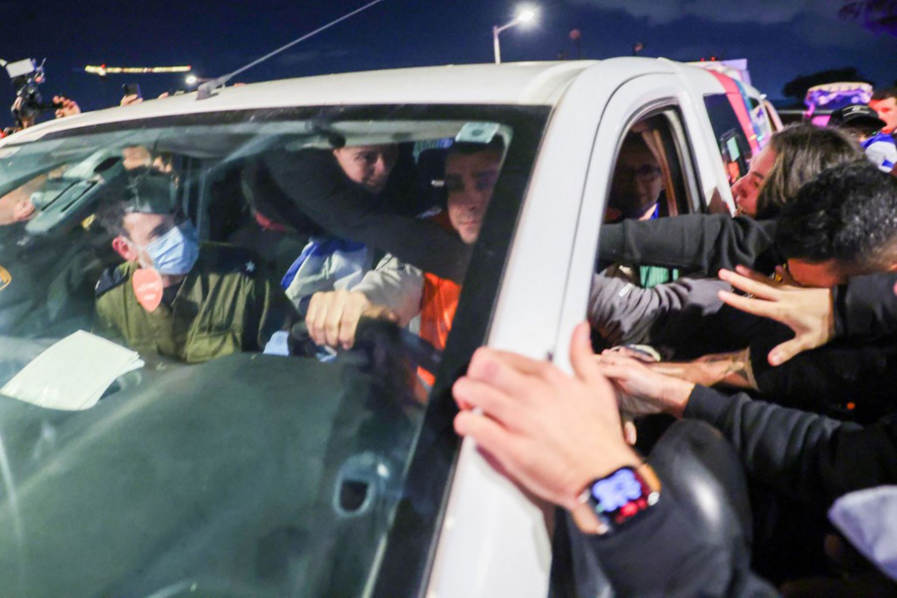 Emily Damari da la mano a sus amigos mientras la transportan con otros dos rehenes al llegar al Centro Médico Sheba Tel HaShomer en Ramat Gan. Foto: AFP