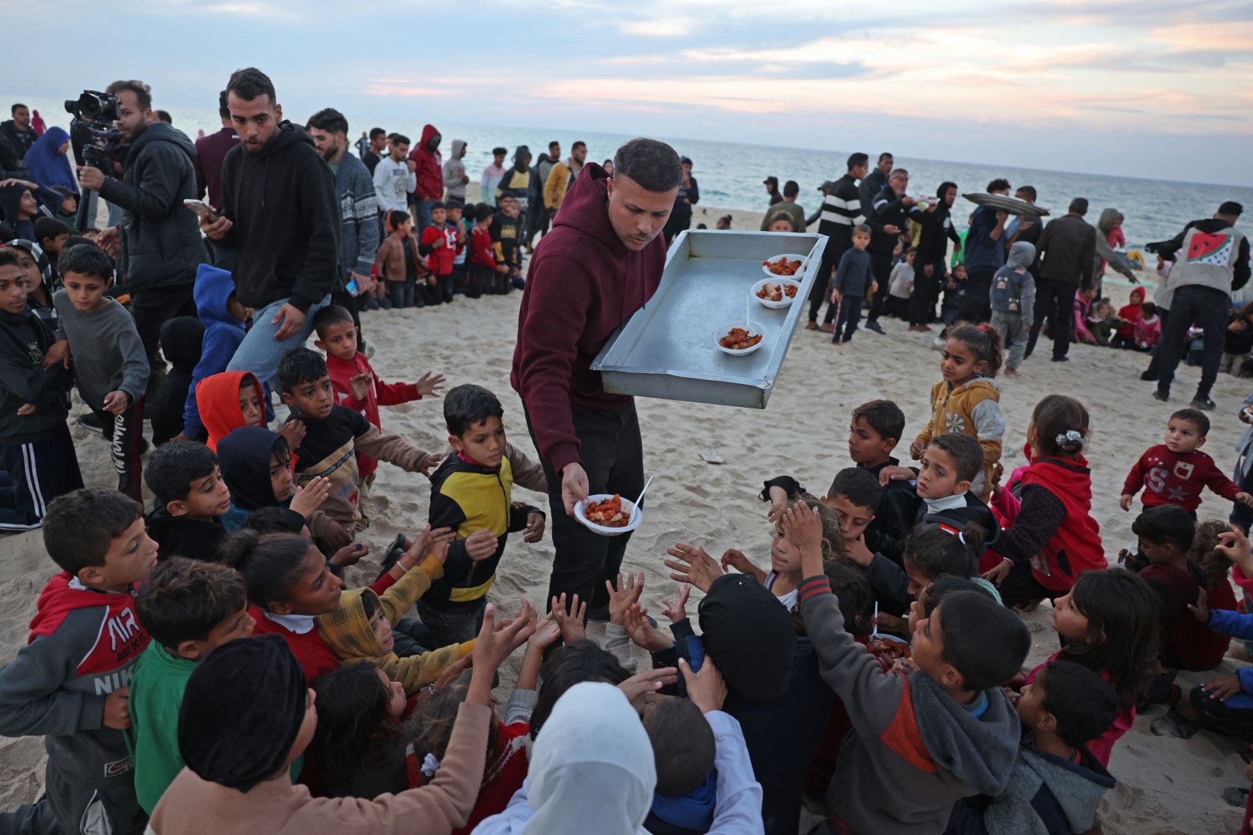 Hamada Shaqoura, un palestino que solía ser un bloguero gastronómico, distribuye comida a los niños después de cocinar una comida para los desplazados, en Khan Yunis, en el sur de la Franja de Gaza. Foto: AFP