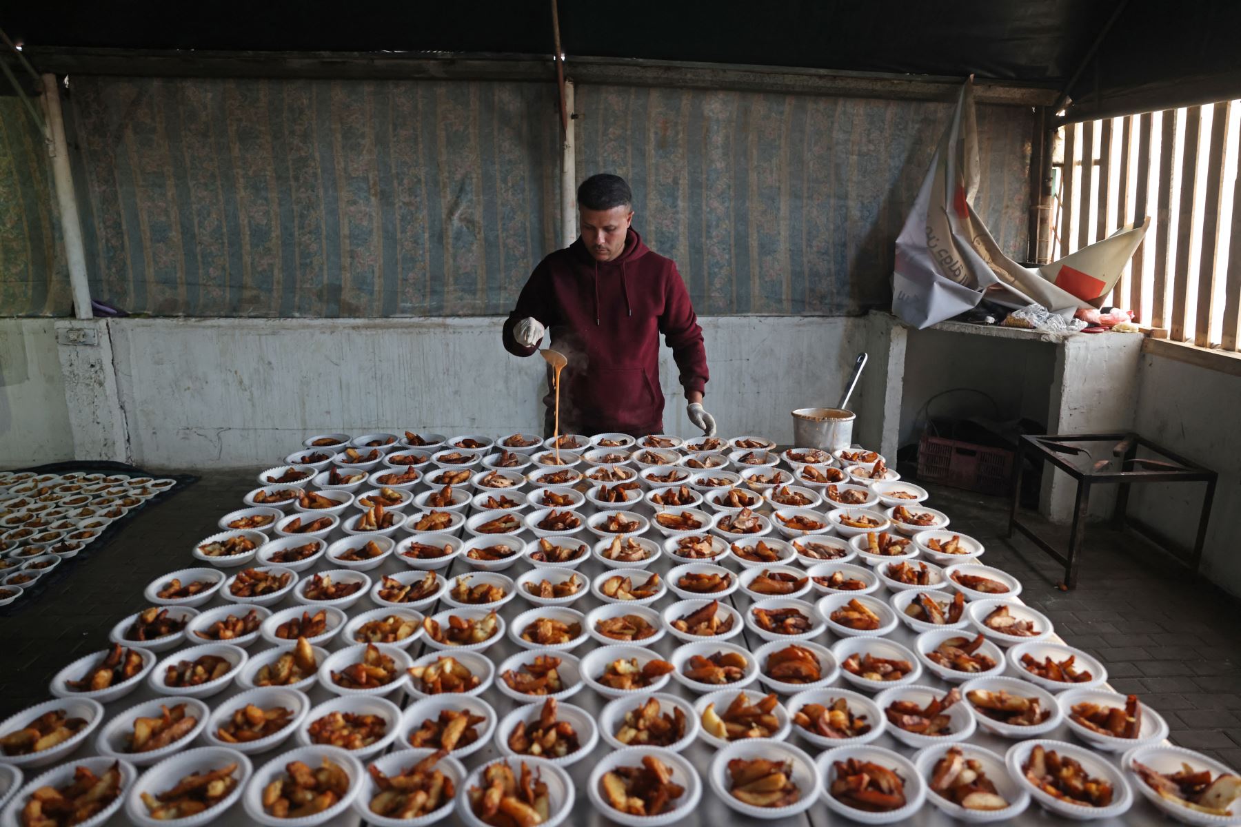 La guerra en la Franja de Gaza entre Israel y Hamás que mató a decenas de miles de personas y creó un desastre humanitario, hizo que Shaqoura dedicara su tiempo a cocinar comidas con raciones de ayuda para alimentar a las personas que viven en campos de refugiados. AFP