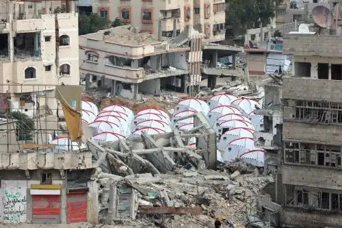 Tiendas de campaña construidas entre los escombros de una construcción en el barrio de Al-Shujiyya, en la ciudad de Gaza. Foto: AFP