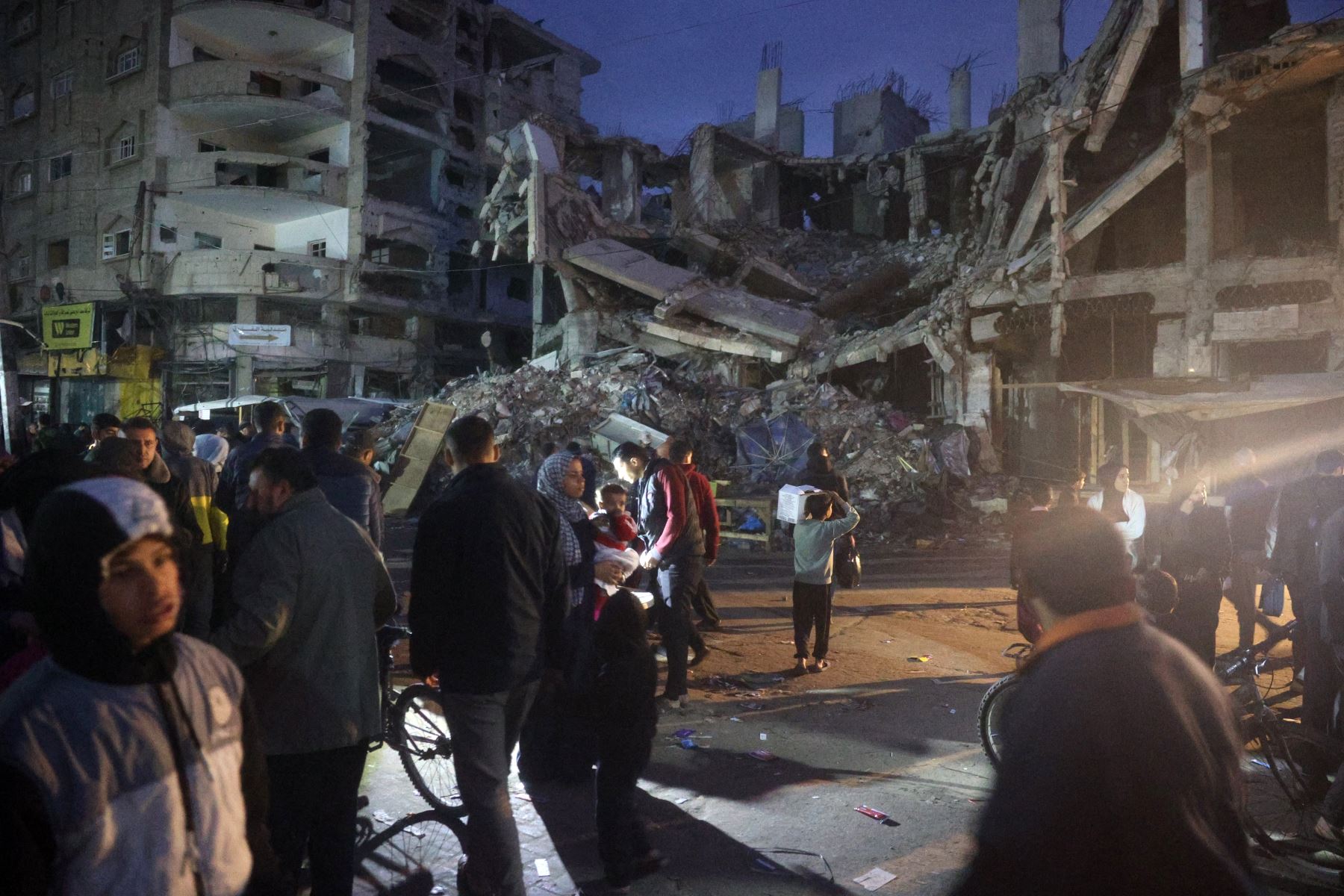 Palestinos desplazados se reúnen en medio de edificios destruidos en Deir el-Balah, en el centro de la Franja de Gaza. AFP