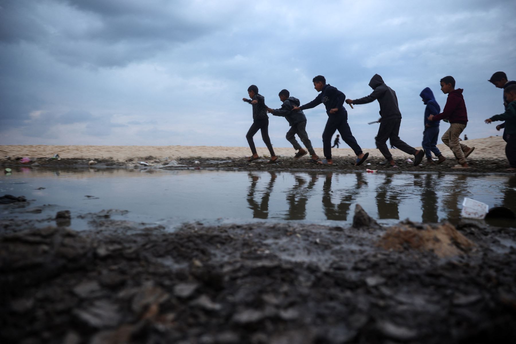 Niños palestinos desplazados juegan cerca de tiendas de campaña a lo largo de una playa en Deir el-Balah, en el centro de la Franja de Gaza. AFP