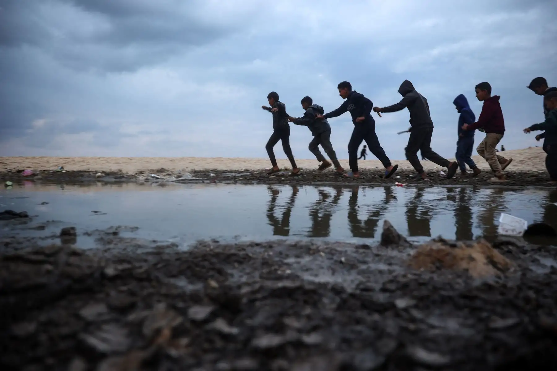 Niños palestinos desplazados juegan cerca de tiendas de campaña a lo largo de una playa en Deir el-Balah, en el centro de la Franja de Gaza. AFP