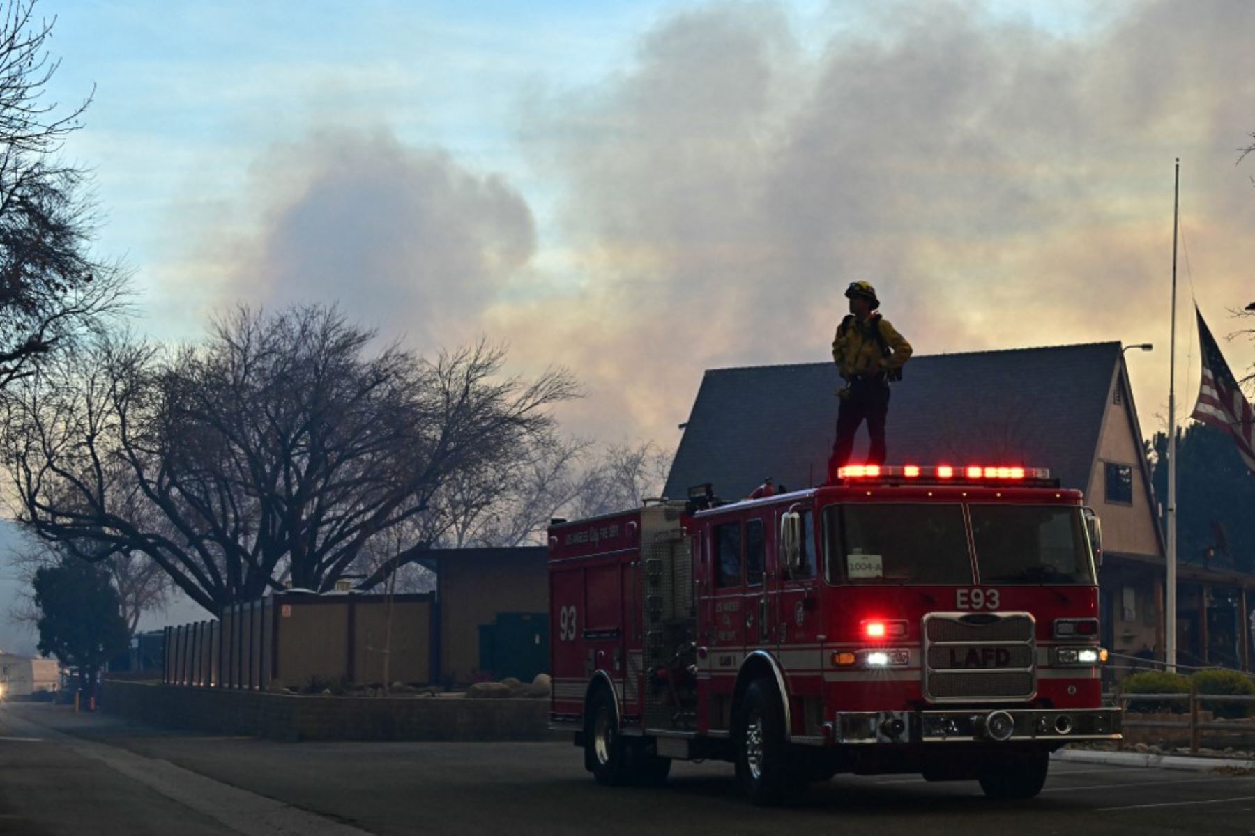 Un bombero se encuentra encima de un camión de bomberos en el parque de casas rodantes de Castaic Lake, en Castaic, California. Foto: AFP