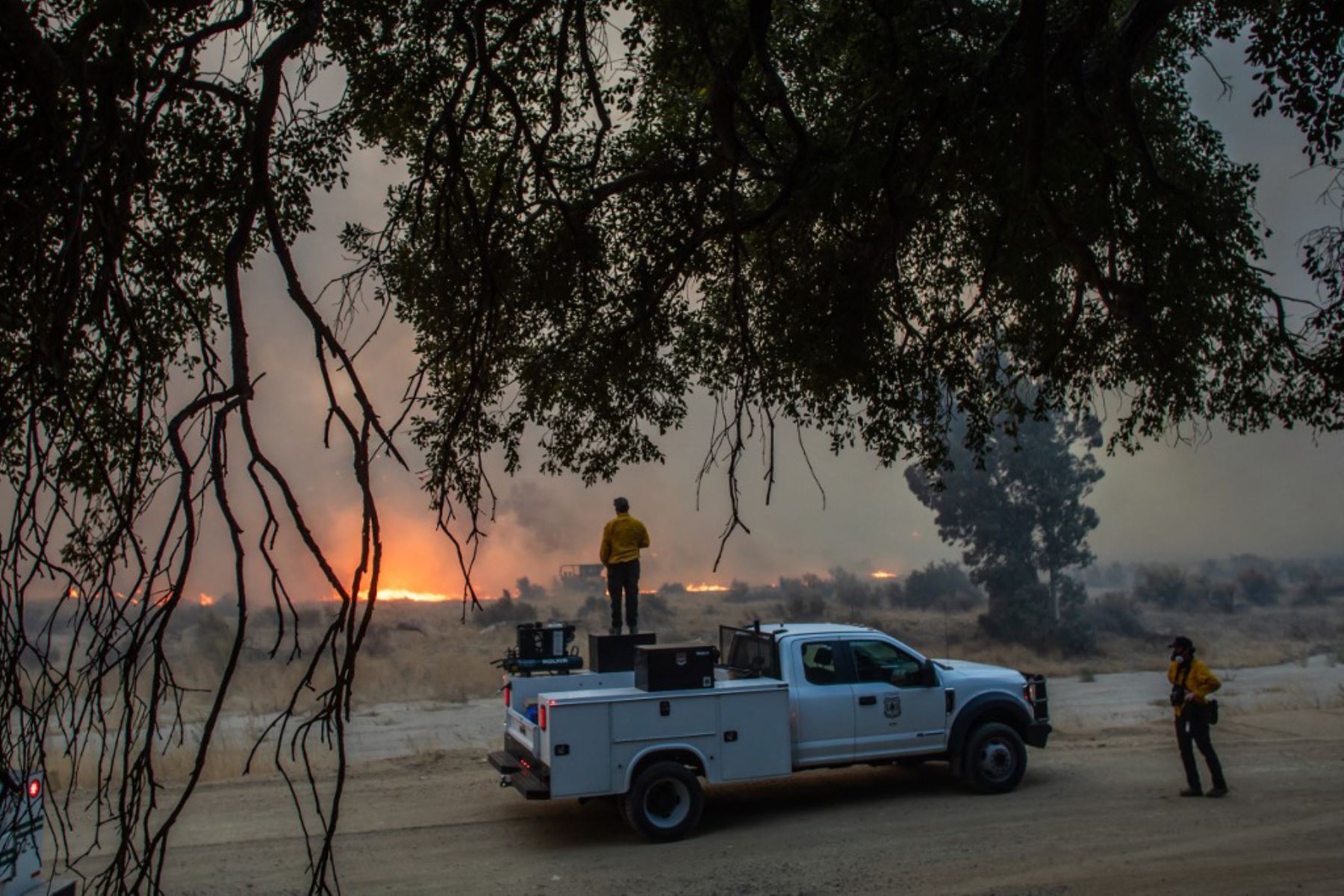 Los bomberos observan cómo arde el incendio Hughes al costado de la carretera en Castaic, un vecindario en el noroeste del condado de Los Ángeles, California. Foto: AFP