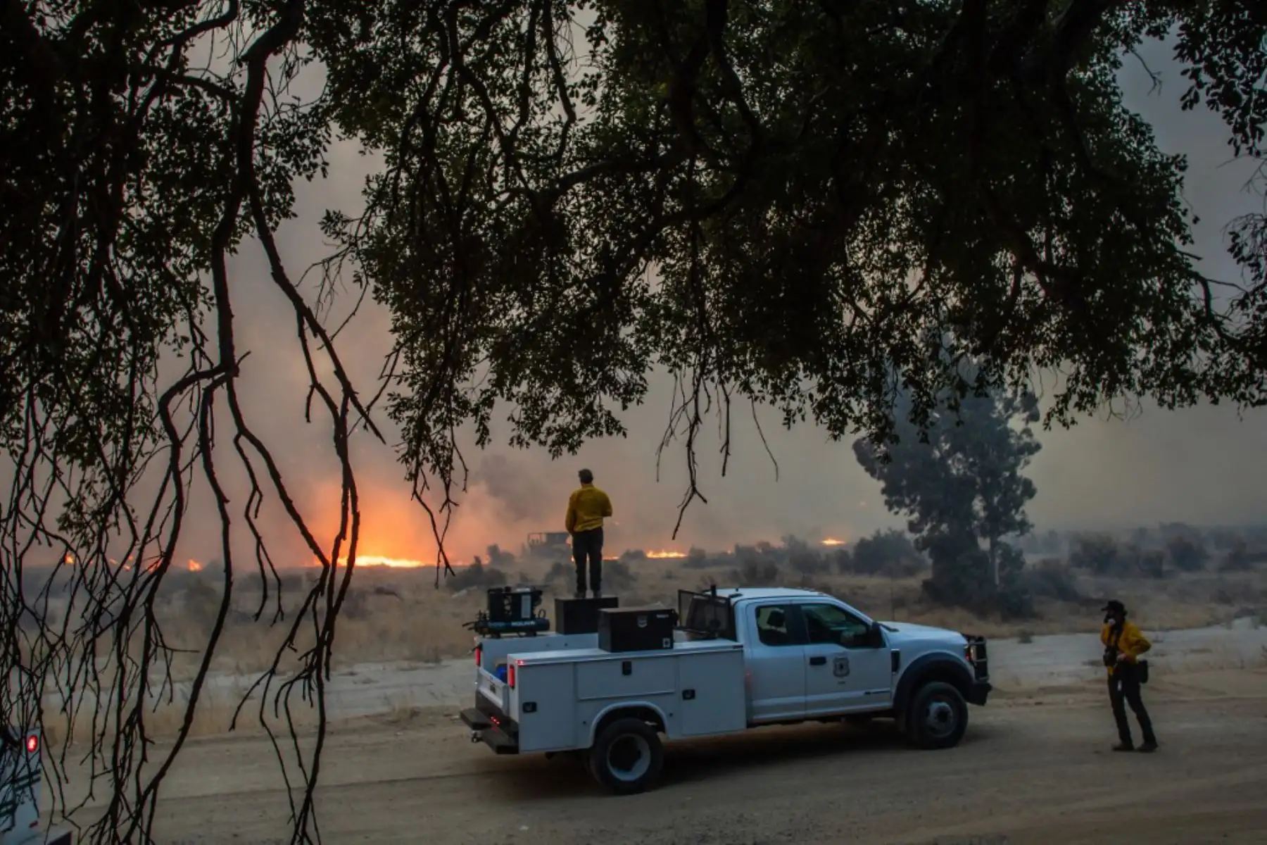 Los bomberos observan cómo arde el incendio Hughes al costado de la carretera en Castaic, un vecindario en el noroeste del condado de Los Ángeles, California. Foto: AFP