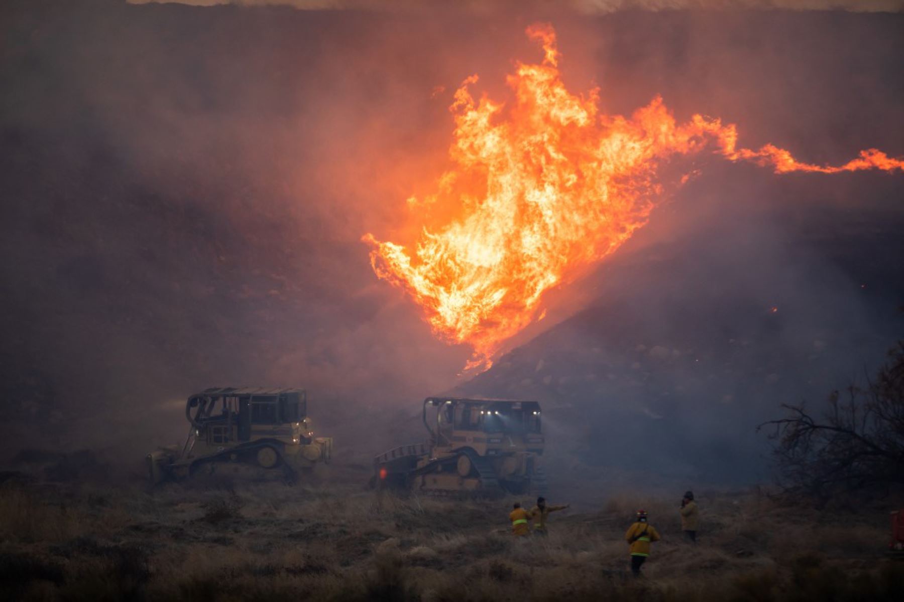 Un operador de excavadora conduce hacia las llamas para establecer una línea de contención para el incendio Hughes en Castaic, un vecindario en el noroeste del condado de Los Ángeles, California. Foto: AFP