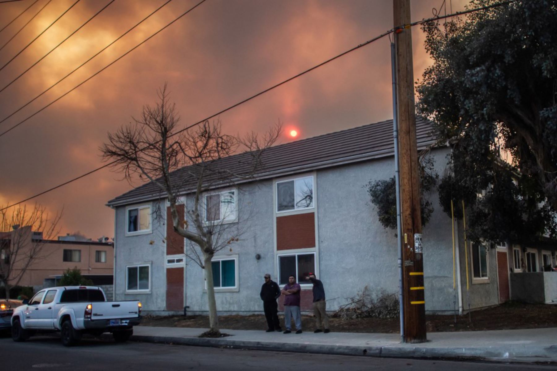 Los residentes locales se encuentran afuera de su casa mientras el cielo se llena de humo del incendio Hughes en Castaic, un vecindario en el noroeste del condado de Los Ángeles, California. Foto: AFP