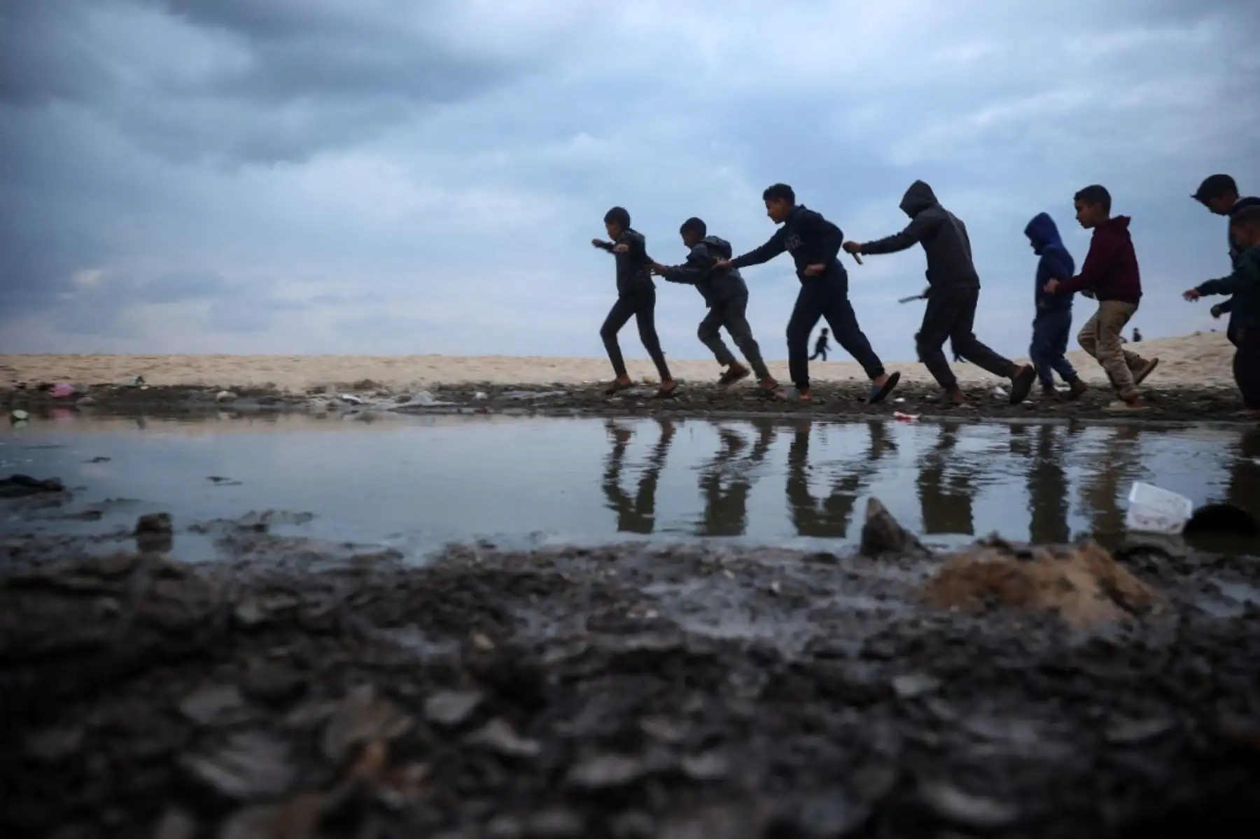 Niños palestinos desplazados juegan cerca de tiendas de campaña a lo largo de una playa en Deir el-Balah, en el centro de la Franja de Gaza, el 22 de enero de 2025, en el cuarto día de un acuerdo de alto el fuego en la guerra entre Israel y Hamas en el territorio palestino. (Foto de Eyad BABA / AFP)