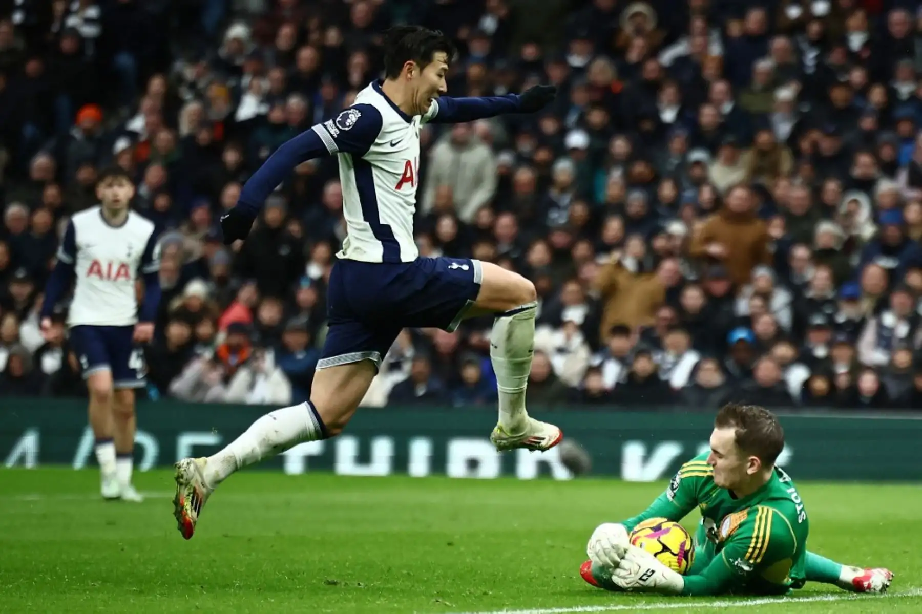 El portero polaco del Leicester City #41 Jakub Stolarczyk (R) salva a los pies del delantero surcoreano del Tottenham Hotspur #07 Son Heung-Min (L) durante el partido de fútbol de la Premier League inglesa entre el Tottenham Hotspur y el Leicester City en el estadio Tottenham Hotspur de Londres, el 26 de enero de 2025. (Foto de HENRY NICHOLLS / AFP)