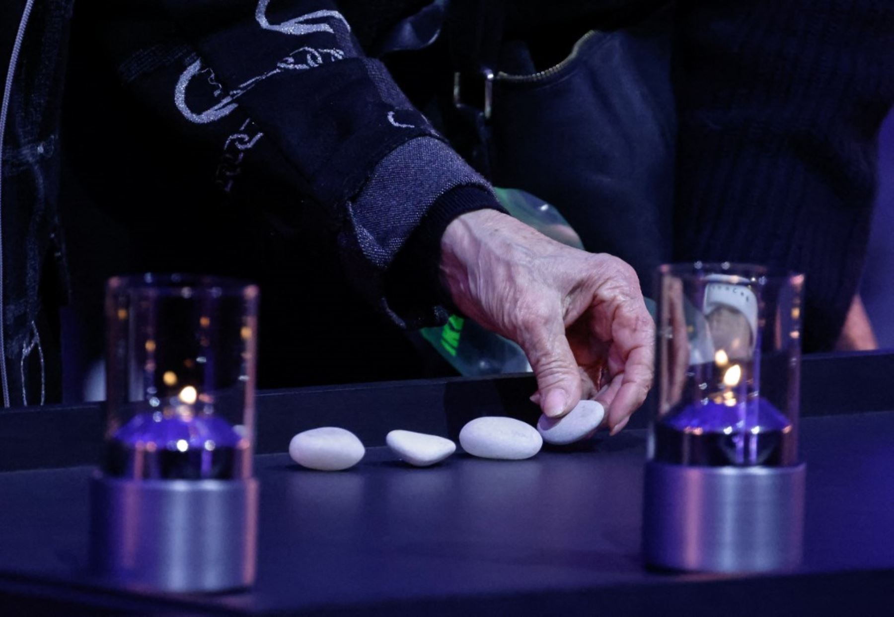 Un sobreviviente del Holocausto coloca piedras entre velas durante las conmemoraciones por el 80 aniversario de la liberación del campo de concentración y exterminio nazi alemán de Auschwitz-Birkenau por parte del Ejército Rojo, en el sitio del campo de concentración de Auschwitz el 27 de enero de 2025, en Oswiecim, Polonia. Foto: AFP