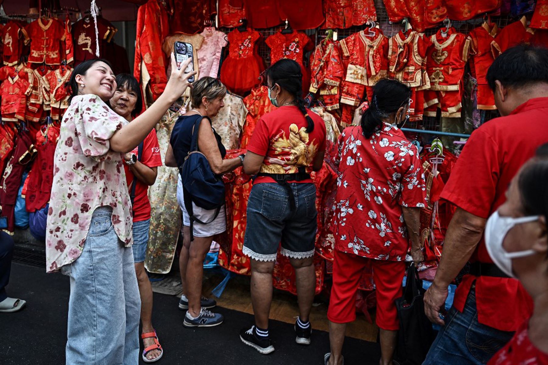 La gente se toma fotografías con puestos que venden ropa roja de estilo chino en el distrito Chinatown de Bangkok , el primer día del Año Nuevo Lunar de la Serpiente. 
Foto: AFP