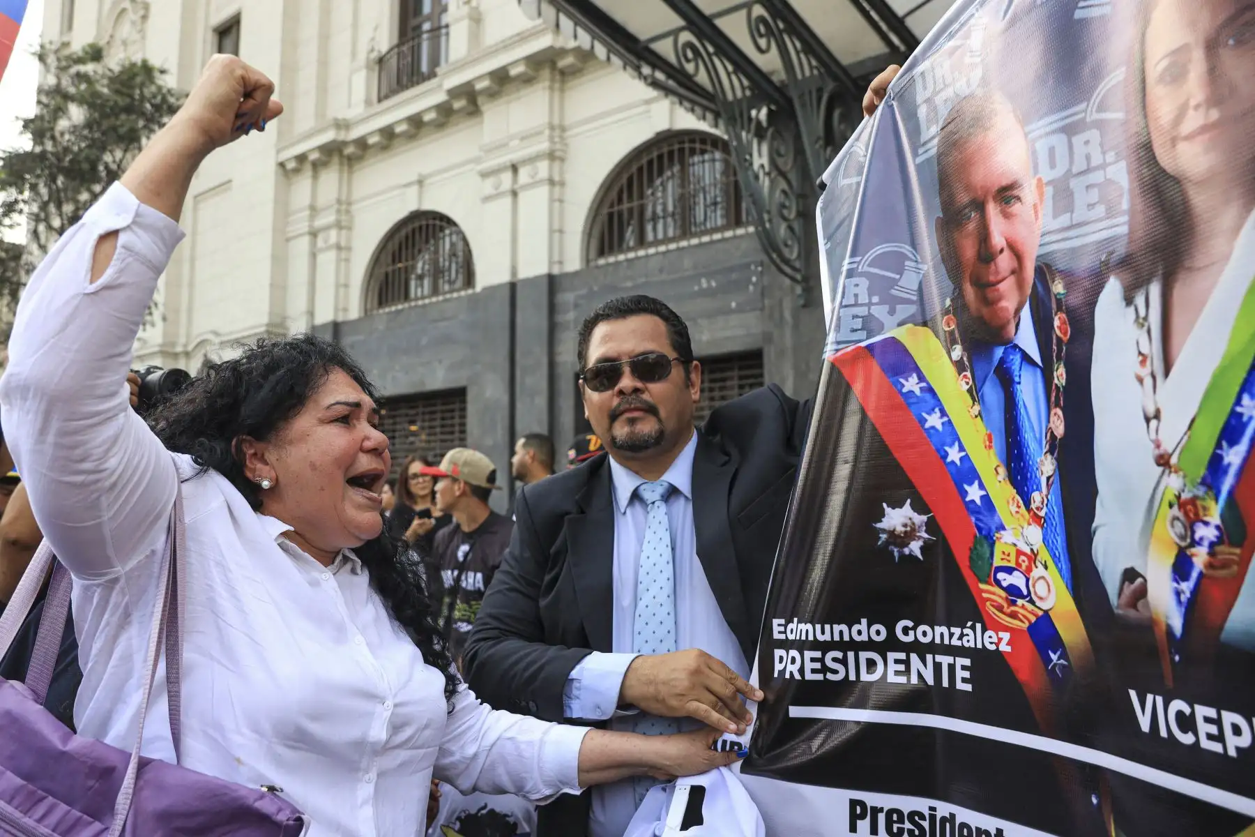 Una ciudadana venezolana hace un gesto frente a un cartel con la imagen de los líderes opositores venezolanos Edmundo González y María Corina Machado en Lima. Foto: AFP