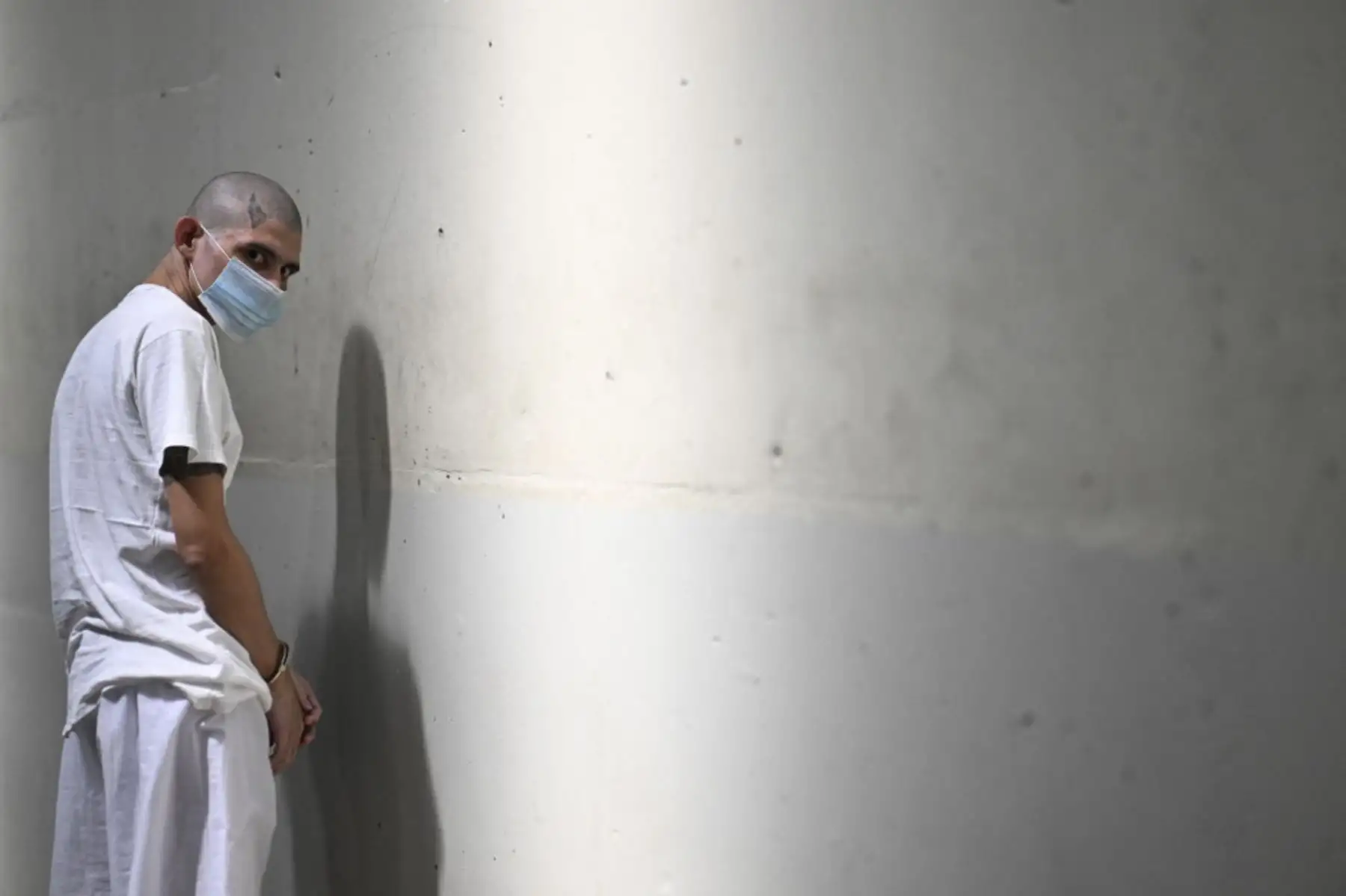 Un recluso esposado mira la megaprisión del Centro de Confinamiento Antiterrorista (CECOT), donde cientos de miembros de las pandillas MS-13 y 18 Street están detenidos, en Tecoluca, El Salvador. La CECOT, la prisión más grande de América Latina y emblema de la guerra contra las pandillas del gobierno del presidente Nayib Bukele, celebra dos años desde que se inauguró. (Foto de Marvin RECINOS / AFP) Un recluso esposado mira la megaprisión del Centro de Confinamiento Antiterrorista (CECOT), donde cientos de miembros de las pandillas MS-13 y 18 Street están detenidos, en Tecoluca, El Salvador. La CECOT, la prisión más grande de América Latina y emblema de la guerra contra las pandillas del gobierno del presidente Nayib Bukele, celebra dos años desde que se inauguró. (Foto de Marvin RECINOS / AFP)