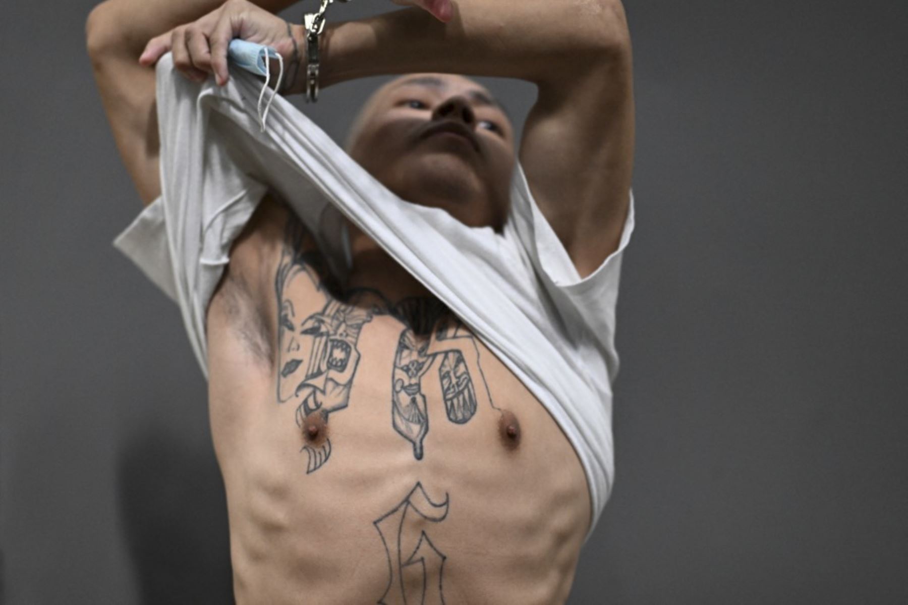 Un pandillero del Barrio 18 (18) sentenciado a más de 200 años de prisión muestra sus tatuajes aludiendo a su pandilla dentro de la megaprisión del Centro de Confinamiento Antiterrorista (CECOT), donde cientos de miembros de las pandillas MS-13 y 18 Street están detenidos, en Tecoluca, El Salvador. La CECOT, la prisión más grande de América Latina y emblema de la guerra contra las pandillas del gobierno del presidente Nayib Bukele, celebra dos años desde que se inauguró el 1 de febre