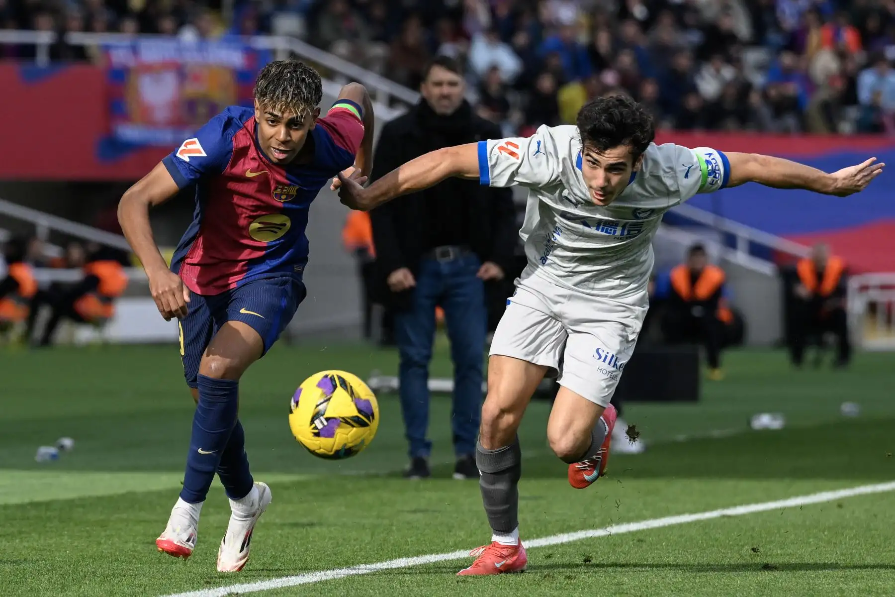 El delantero español del Barcelona, Lamine Yamal  corre por el balón con el defensor español del Alavés, Manuel Sánchez durante el partido de fútbol de la liga española entre el FC Barcelona y el Deportivo Alavés.
Foto. AFP