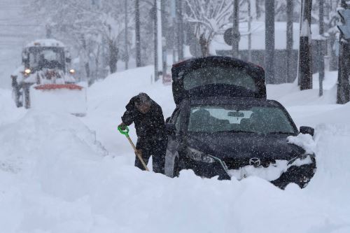 Un hombre intenta sacar su vehículo con una pala mientras cae nieve en el norte de Japón, en la ciudad de Obihiro, prefectura de Hokkaido. Foto: AFP