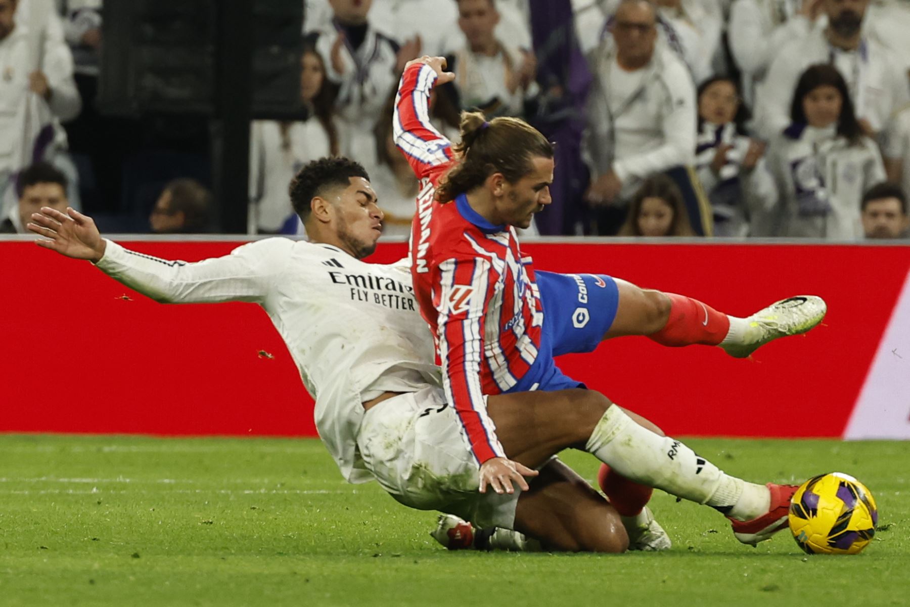 El centrocampista británico del Real Madrid Jude Bellingham (i) lucha con el francés Antoine Griezmann, del Atlético de Madrid, durante el partido de la jornada 23 de LaLiga de fútbol que Real Madrid y Atlético de Madrid disputan este sábado en el estadio Santiago Bernabéu. Foto: EFE