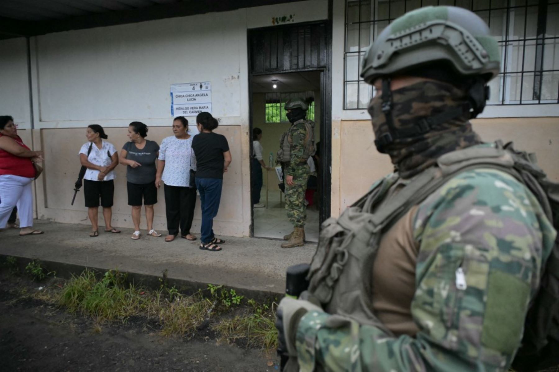 El personal militar hace guardia mientras las mujeres hacen cola para votar en un colegio electoral en Canuto, Ecuador, el 9 de febrero de 2025, durante las elecciones presidenciales. Unos 14 millones de ecuatorianos comenzaron a votar el domingo para decidir quién liderará a la nación andina devastada por la violencia a través de su peor crisis en medio siglo. (Foto de Rodrigo BUENDIA / AFP)