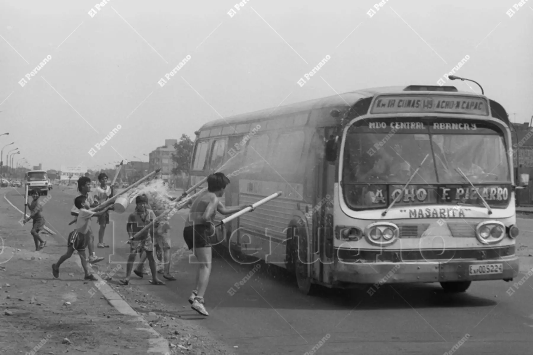 Lima  - 24 febrero 1991 /  Niños provistos de chisguetes lanzan potentes chorros de agua a un ómnibus de la línea 149 en el último domingo de carnaval. Foto: Archivo Histórico de El Peruano / Onésimo Bottoni