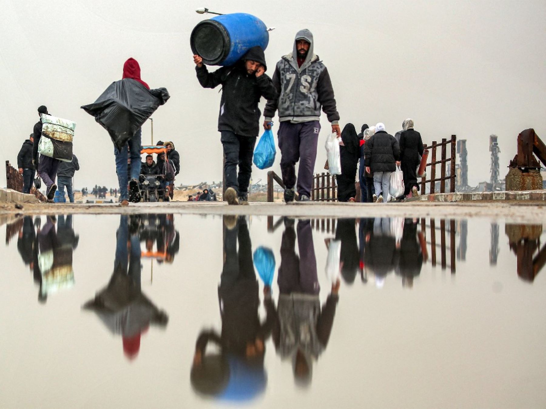 La gente camina con sus pertenencias a lo largo del puente de Wadi Gaza a lo largo de la calle al-Rashid entre la ciudad de Gaza y Nuseirat en la Franja central de Gaza el 10 de febrero de 2025 mientras los desplazados regresan a casa en medio del actual acuerdo de alto el fuego en la guerra entre Israel y Hamas. (Foto de Eyad BABA / AFP)