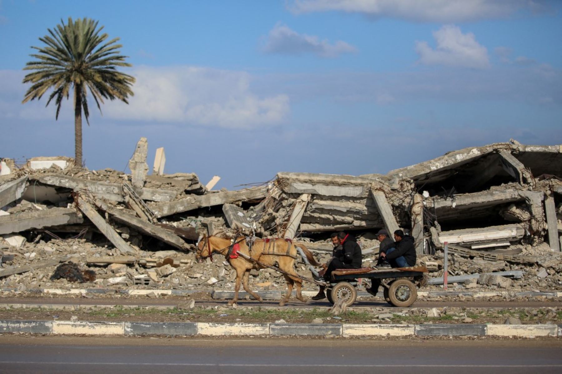 Civiles se transportan en una carreta jalada por un caballo frente a los escombros de un edificio destruido en al-Mughraqa, en el centro de la Franja de Gaza, el 13 de febrero de 2025, mientras los desplazados se mueven hacia las partes norte de Gaza durante un actual acuerdo de alto el fuego en la guerra entre Israel y Hamas. (Foto de Eyad BABA / AFP)