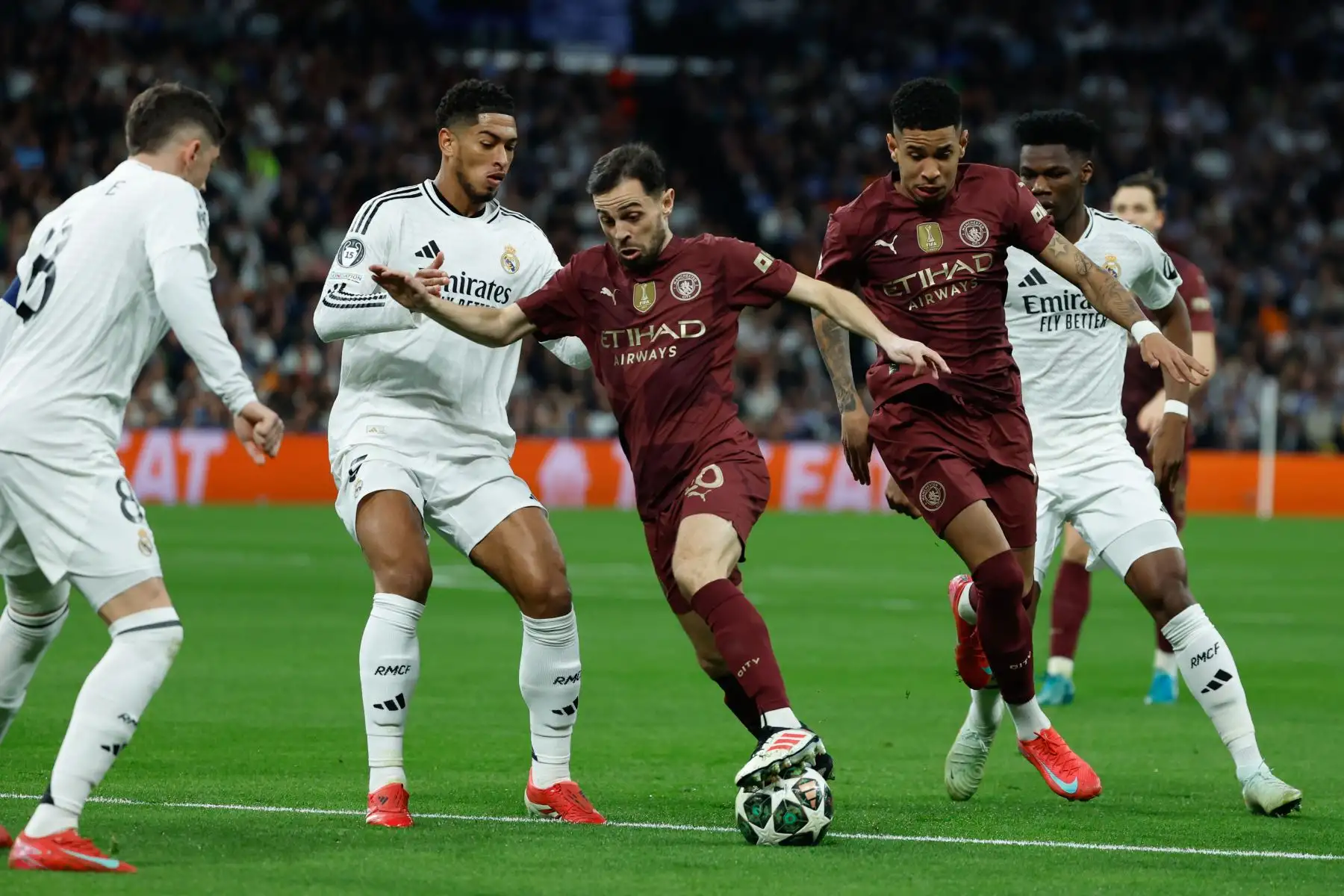 El centrocampista portugués del Manchester City Bernardo Silva intenta superar al británico Jude Bellingham, del Real Madrid, durante el partido de vuelta de los dieciseisavos de final de la Liga de Campeones que Real Madrid y Manchester City. Foto: ANDINA/ EFE