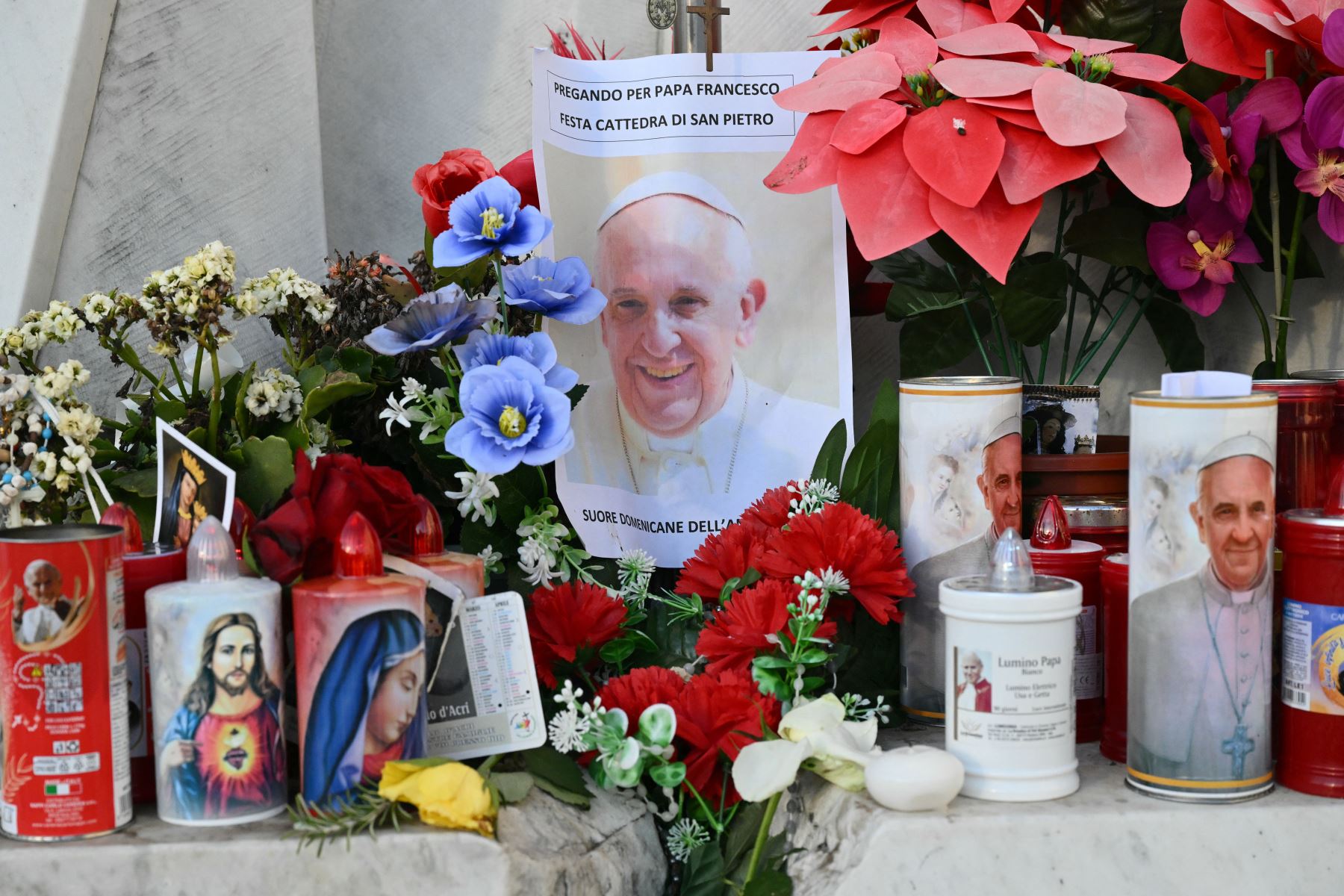 Se colocan velas, flores y un retrato del Papa Francisco frente a la estatua de Juan Pablo II afuera del hospital Gemelli donde el Papa Francisco está hospitalizado en Roma.
Foto: AFP