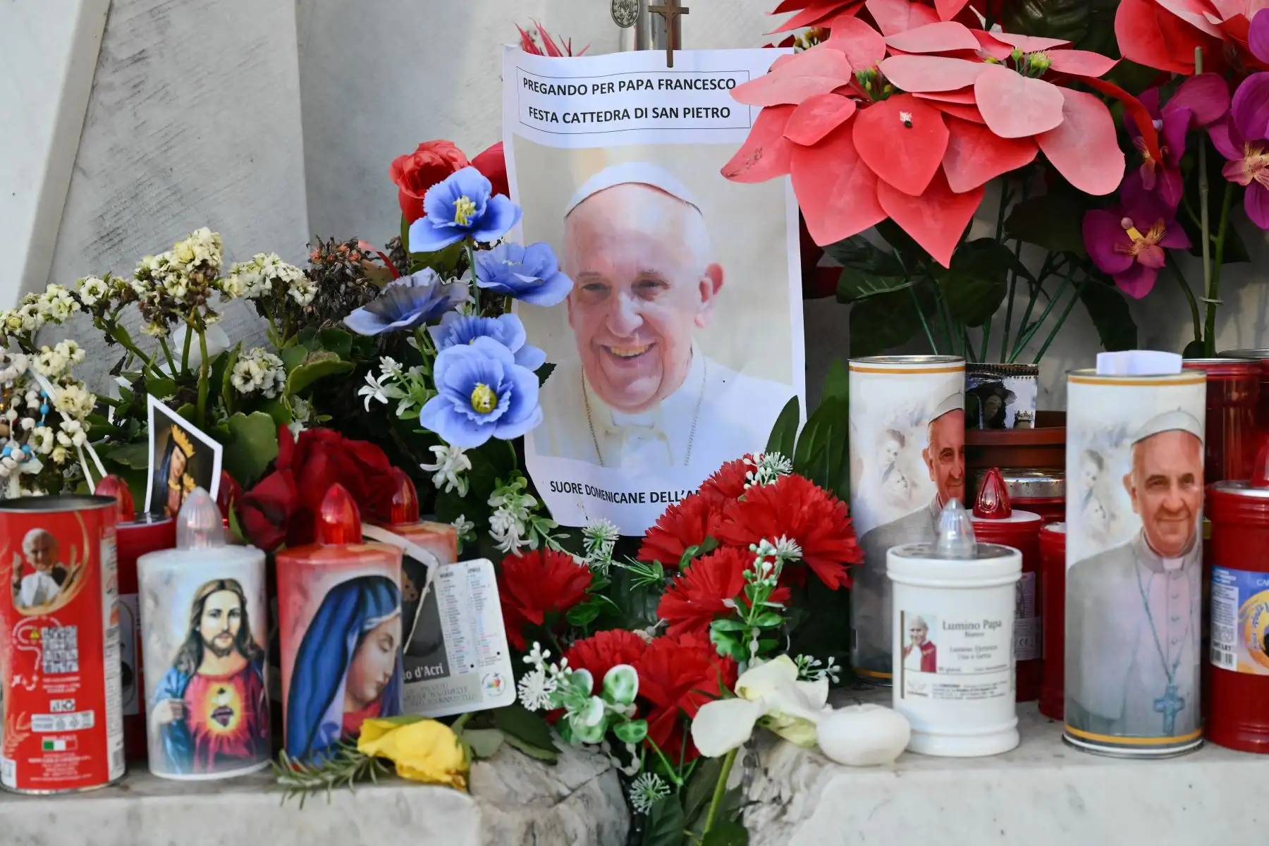 Se colocan velas, flores y un retrato del Papa Francisco frente a la estatua de Juan Pablo II afuera del hospital Gemelli donde el Papa Francisco está hospitalizado en Roma.
Foto: AFP
