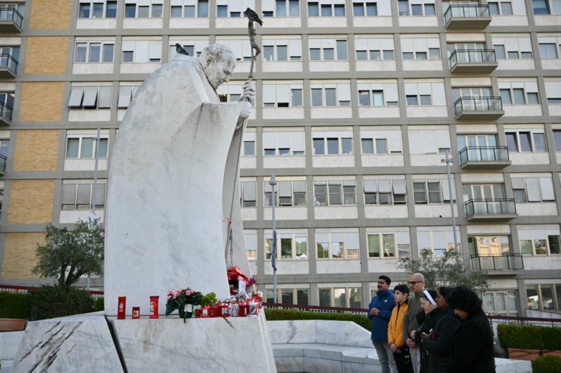 La gente reza en la estatua de Juan Pablo II fuera del hospital Gemelli, donde el Papa Francisco está hospitalizado por neumonía, en Roma el 23 de febrero de 2025. El Papa Francisco tuvo una noche tranquila en el hospital, dijo el Vaticano el 23 de febrero de 2025, la mañana después de revelar que el hombre de 88 años se encontraba en un estado "crítico". "La noche pasó pacíficamente, el Papa descansó", dijo la Santa Sede en una breve actualización. (Foto de Alberto PIZZOLI / AFP)